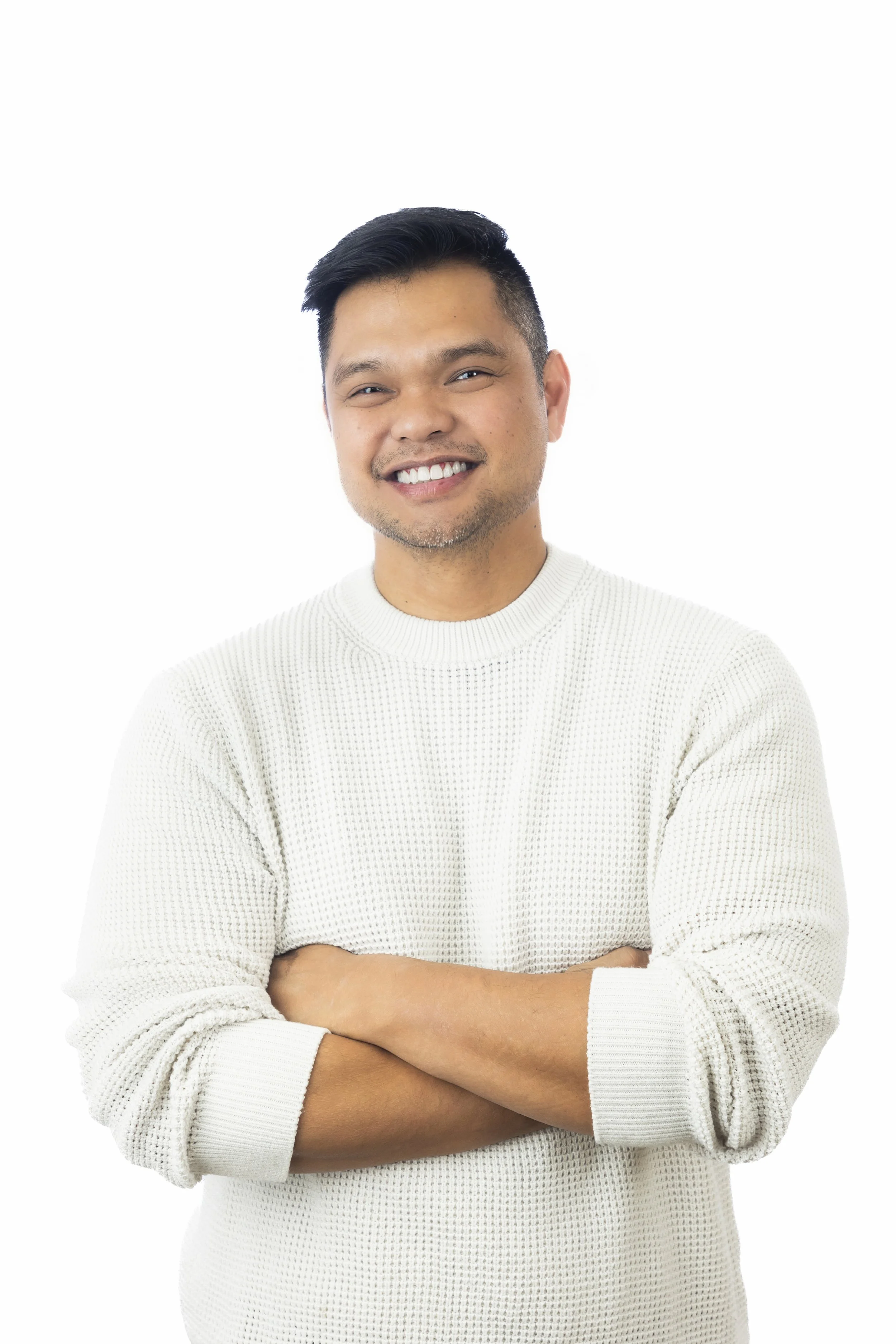 A smiling man with crossed arms wearing a white sweater against a plain white background.