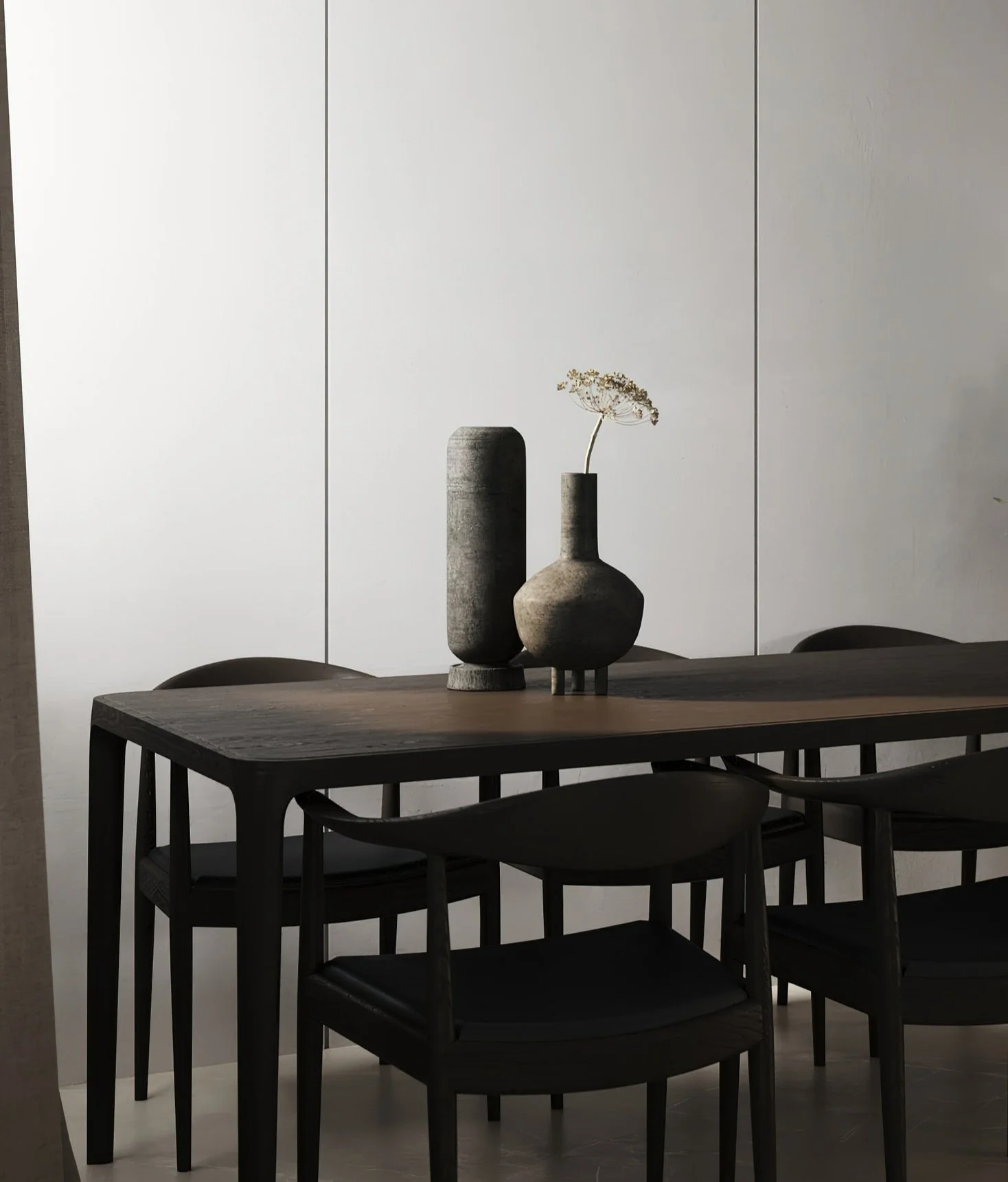 Minimalist dining room with a dark wooden table, black chairs, and decorative vases on the table, with a white wall background.