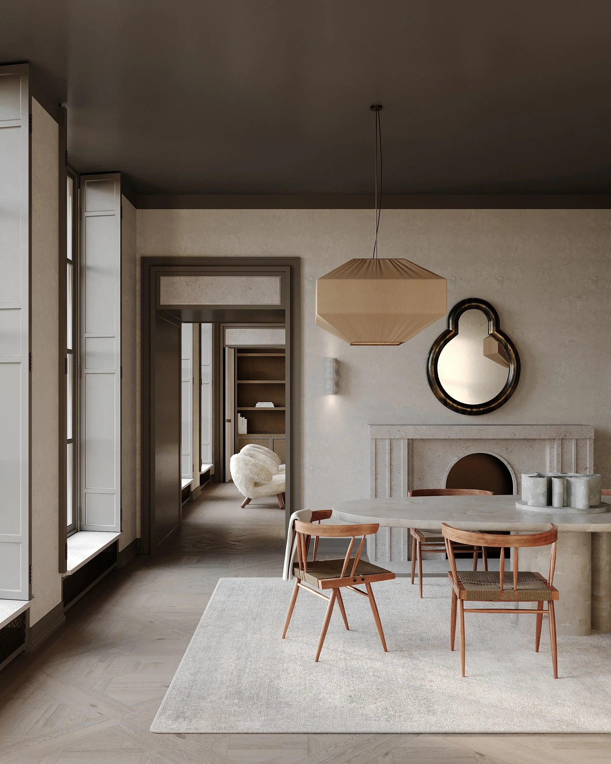 Modern dining room with round white table, three wooden chairs, large beige pendant light, mirror with black frame, and fireplace with a beige mantle. A hallway with bookshelves and a white armchair is visible in the background.