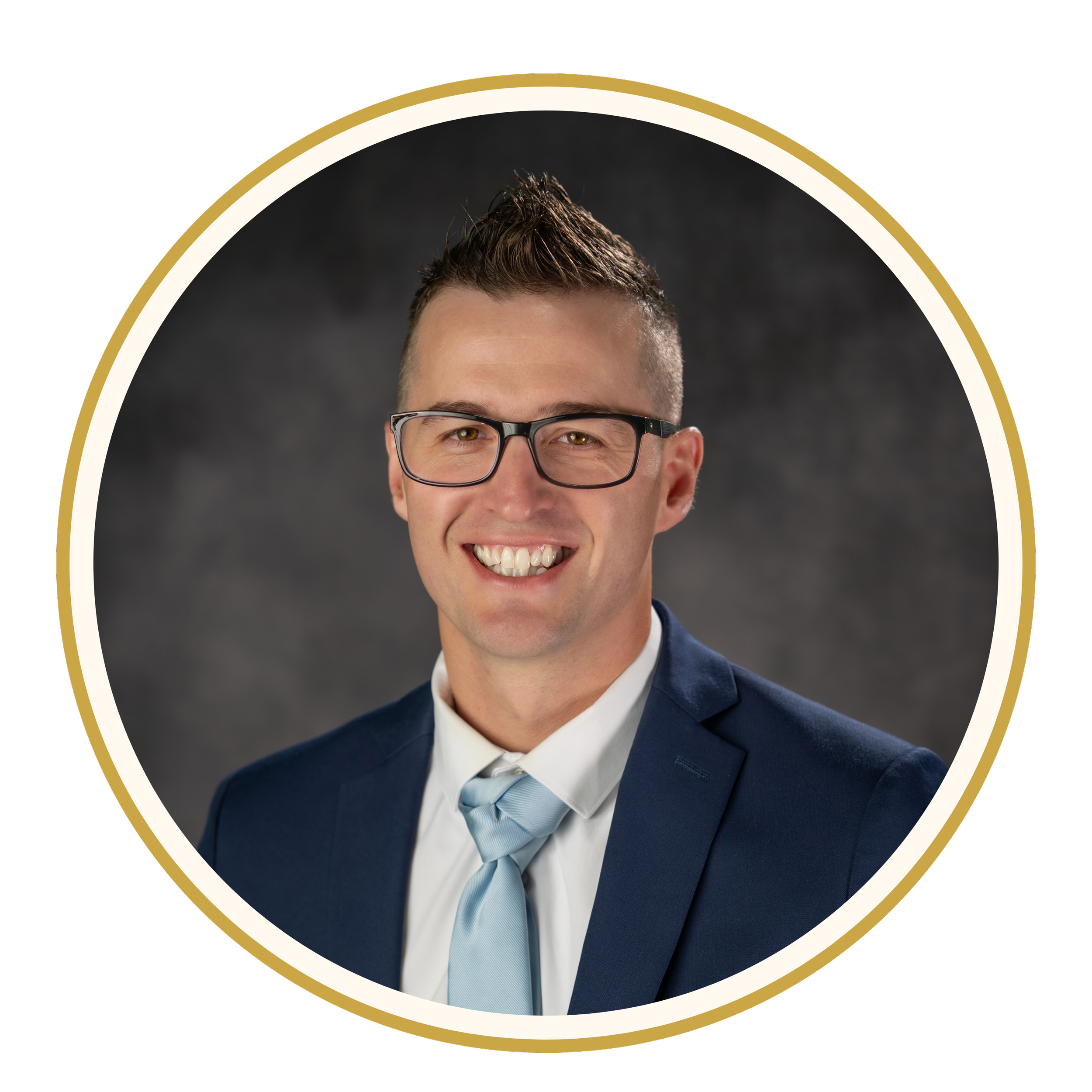 Headshot of a man with short brown hair, wearing glasses, a navy blue suit, white shirt, and light blue tie, smiling against a dark background.