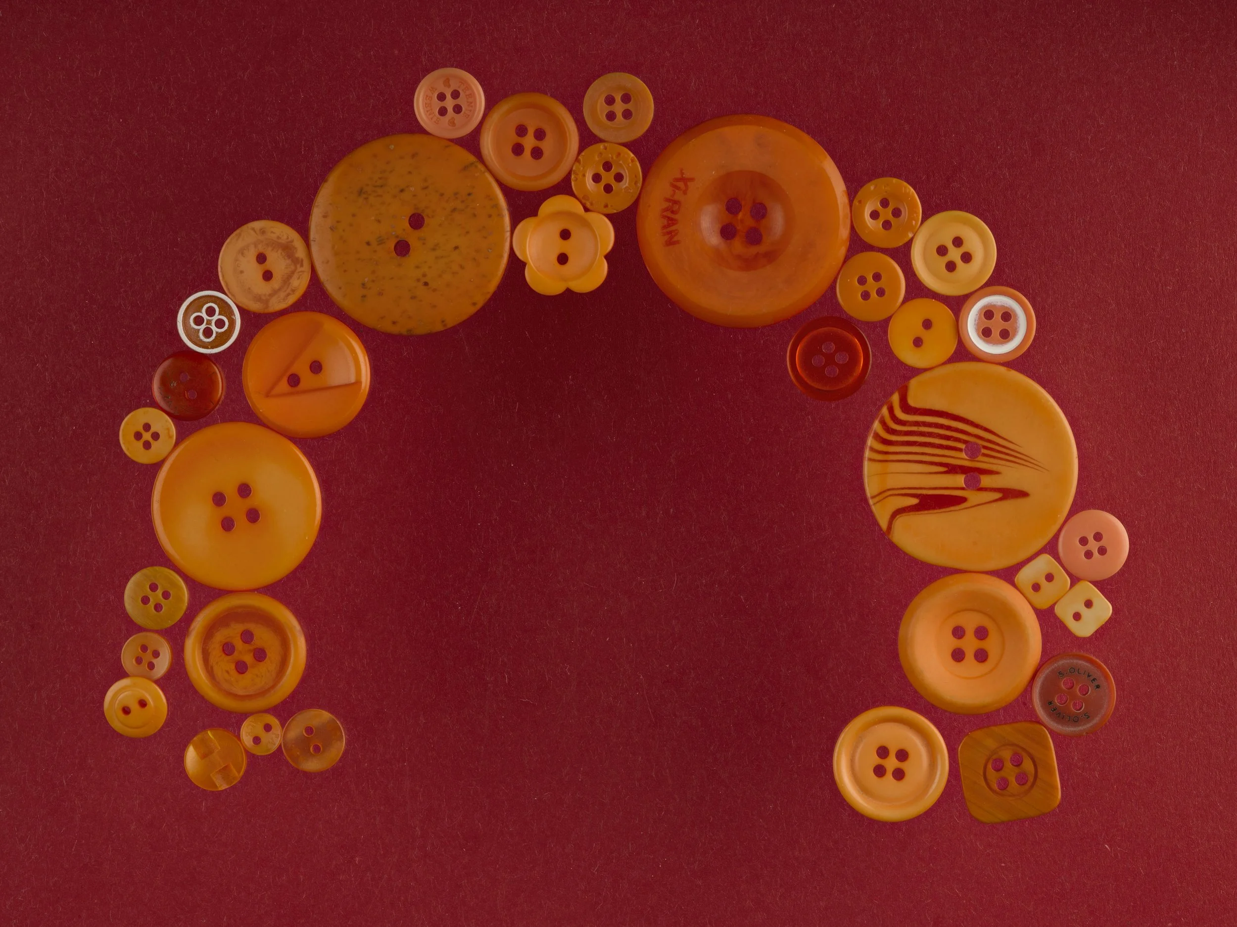 Collection of various orange and red buttons arranged in an arc on a red background.