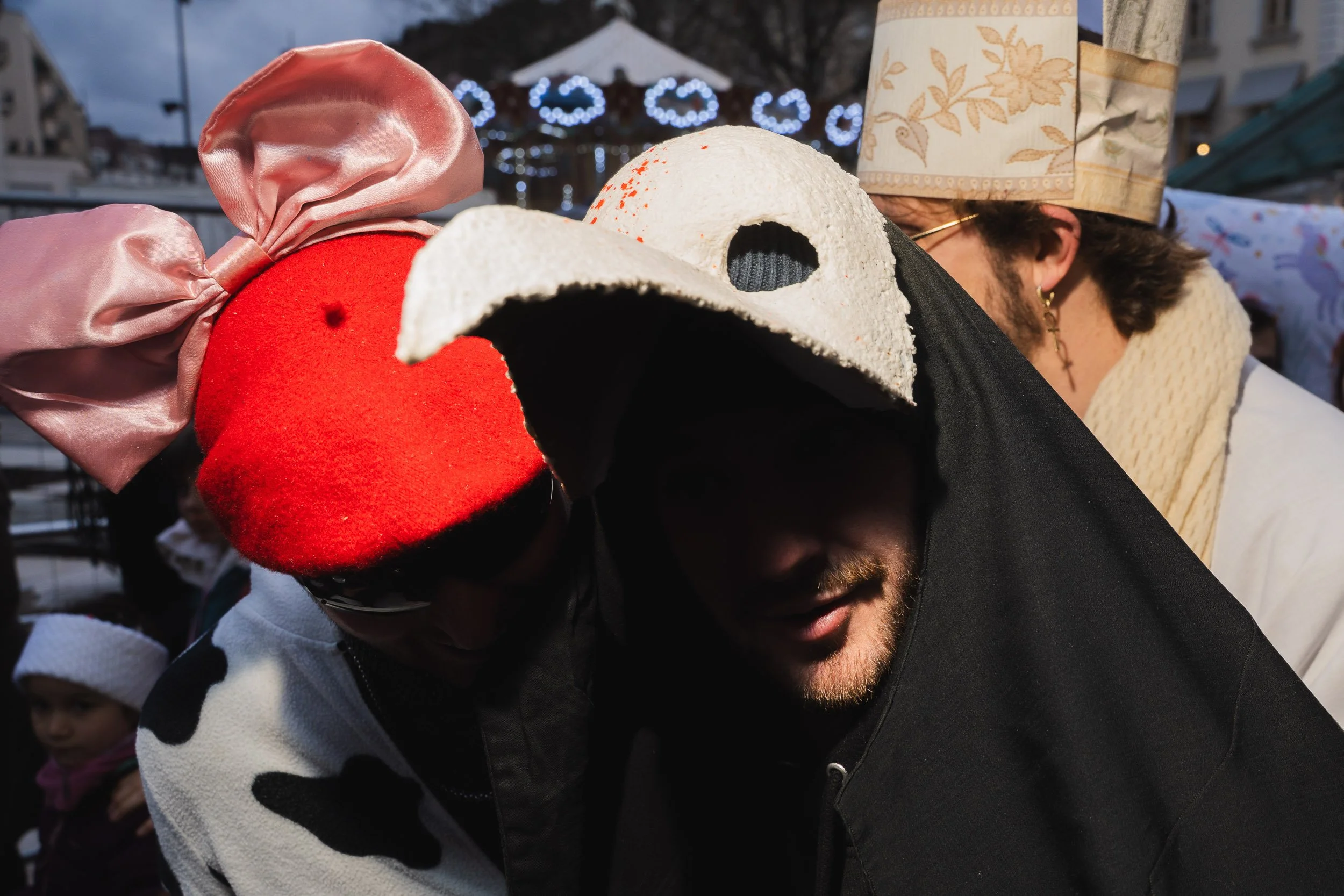 People wearing costumes, including a cow costume and a chicken costume, at an outdoor event during evening or dusk.
