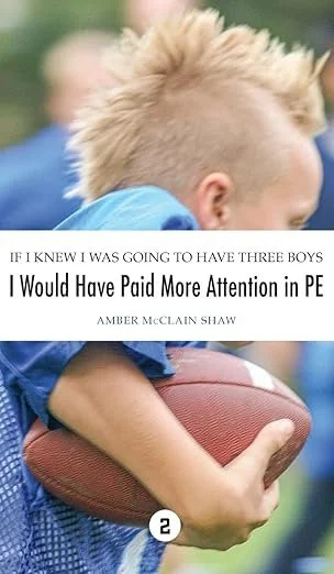 A young boy with a mohawk hairstyle holding a football. There is a quote overlay that reads, 'If I knew I was going to have three boys I would have paid more attention in PE' by Amber McClain Shaw.