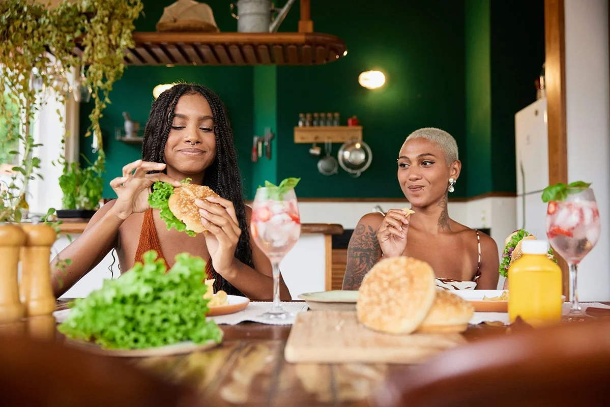 two smiling women eating veggie burgers