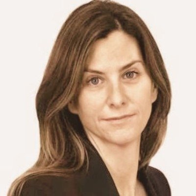 A woman with brown hair and light skin looking at the camera against a light background.