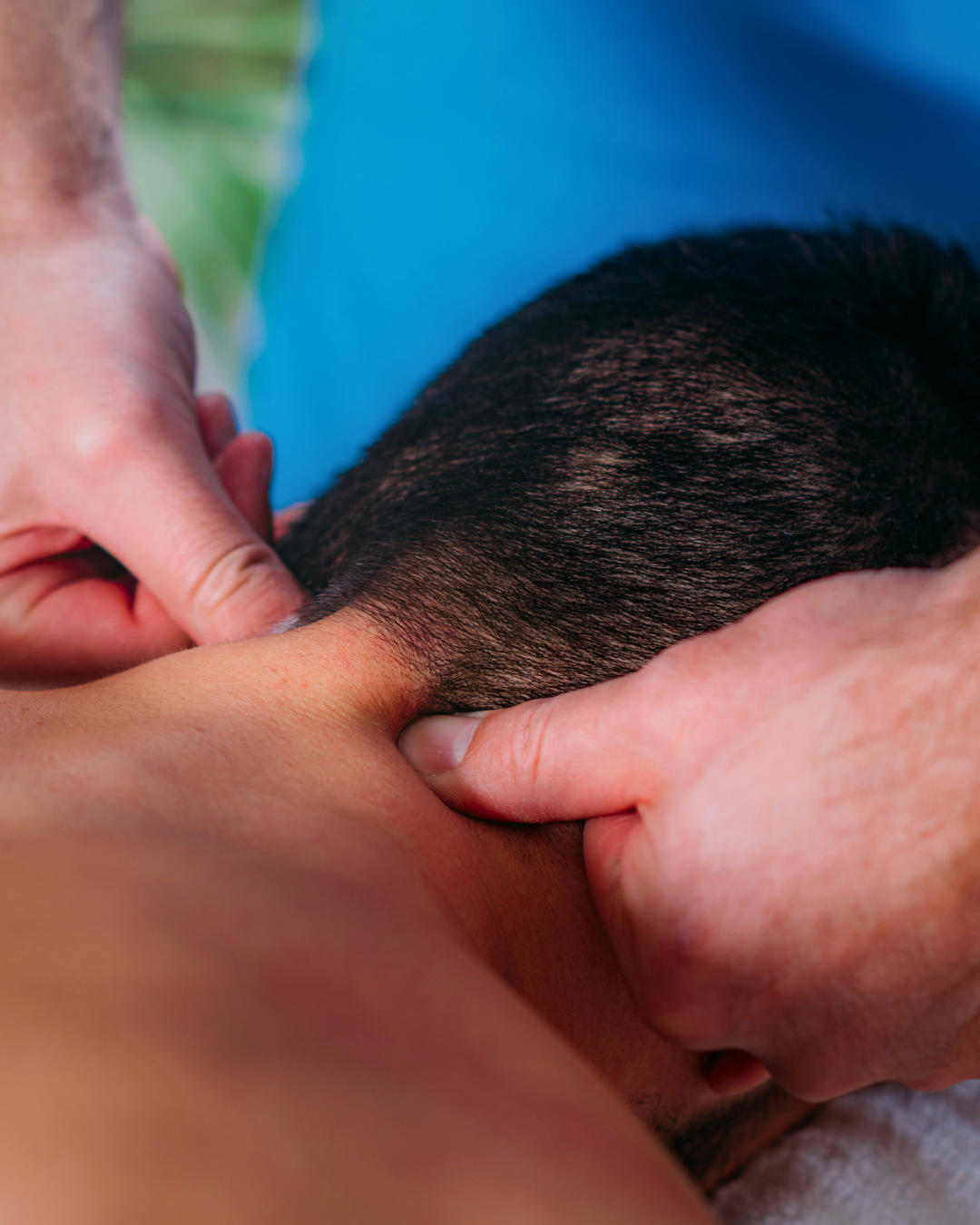 A person receiving a massage on their neck and shoulder area, with close-up view of hands massaging.
