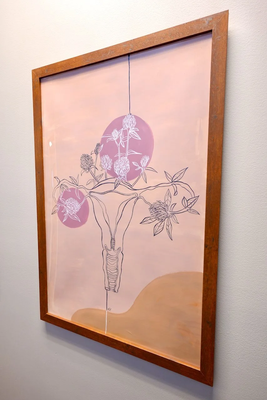 Framed artwork depicting a botanical illustration of a flowering plant with roots, branches, and leaves, with abstract pink circles and a pink background.