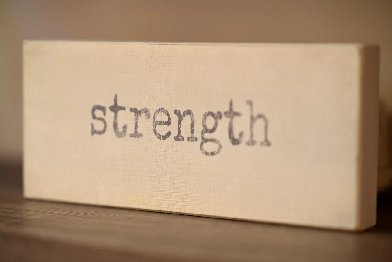 Close-up of a wooden block with the word 'strength' printed on it.