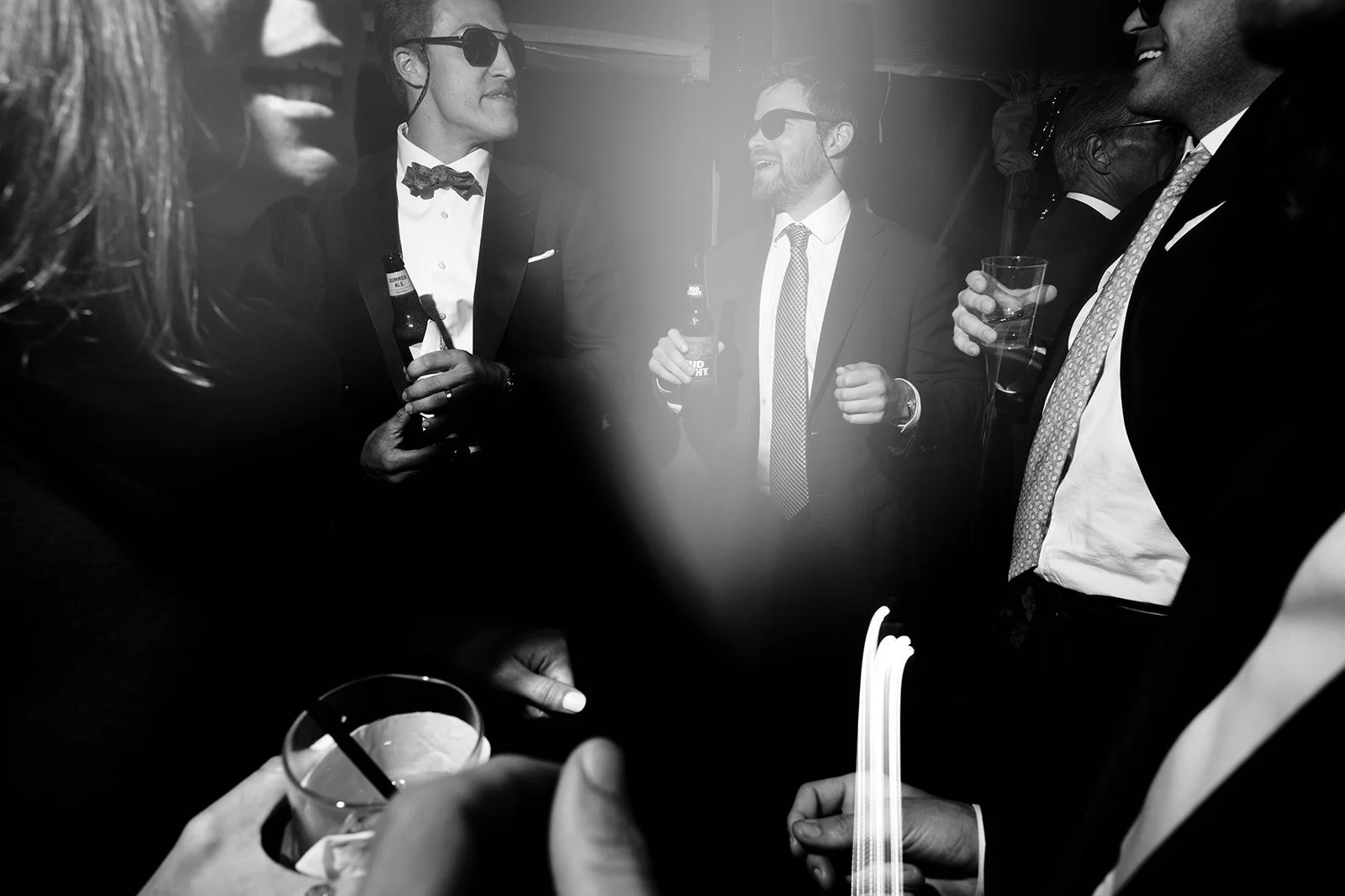 Group of people at a party, wearing formal attire, holding drinks, and engaging in conversation.