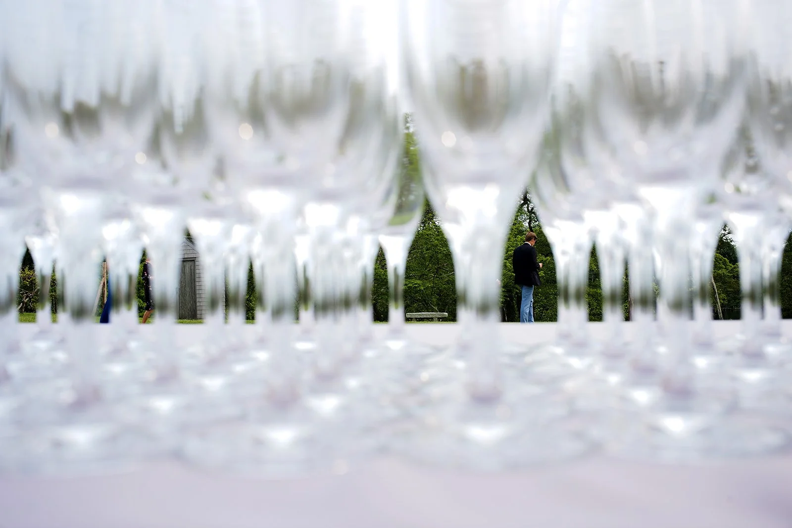 Multiple empty champagne glasses viewed from below, with people and greenery seen in the background.