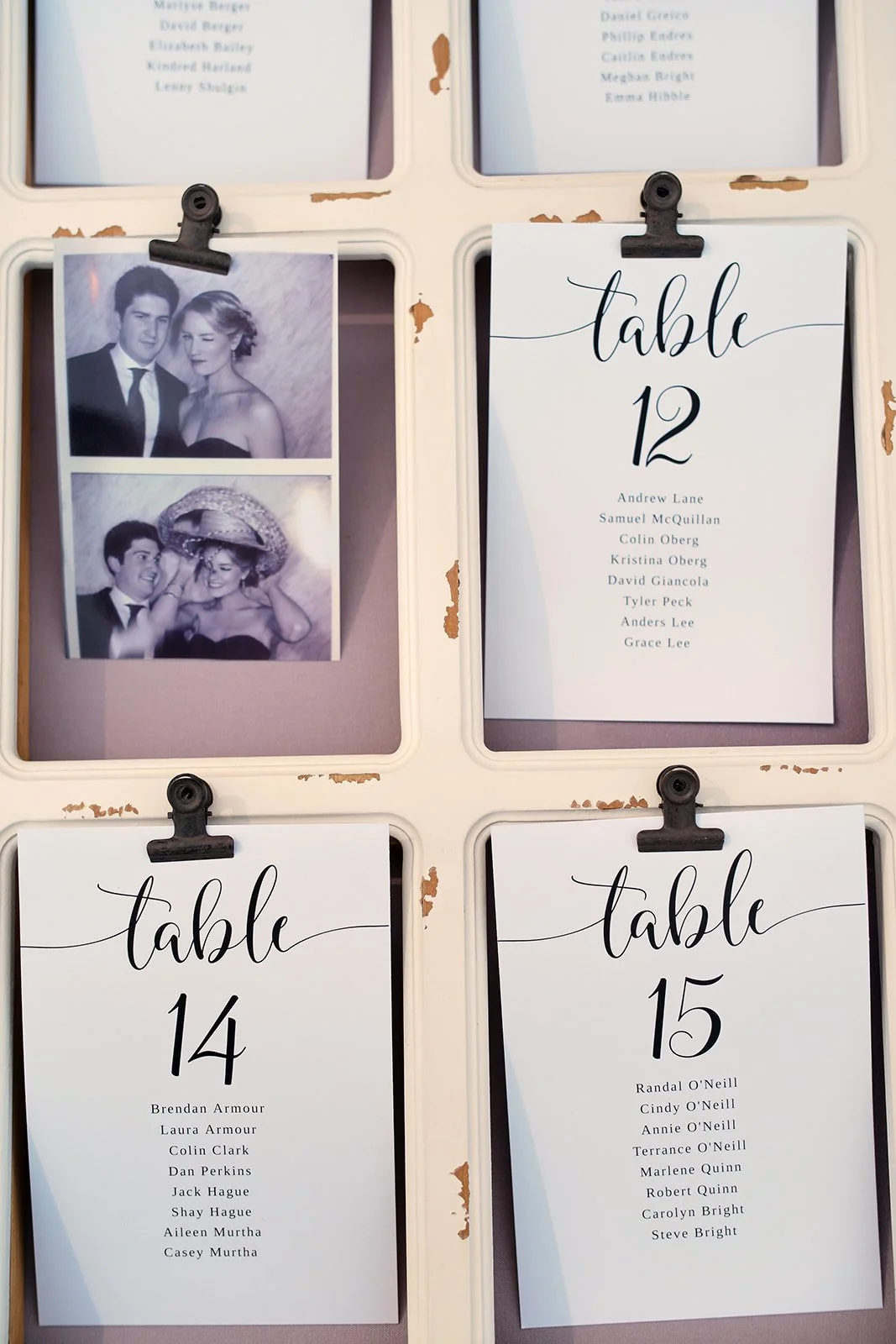 Photo booth pictures showing a couple, one dressed formally and the other wearing a large hat, at a wedding reception. There are four table number cards with guest names displayed.