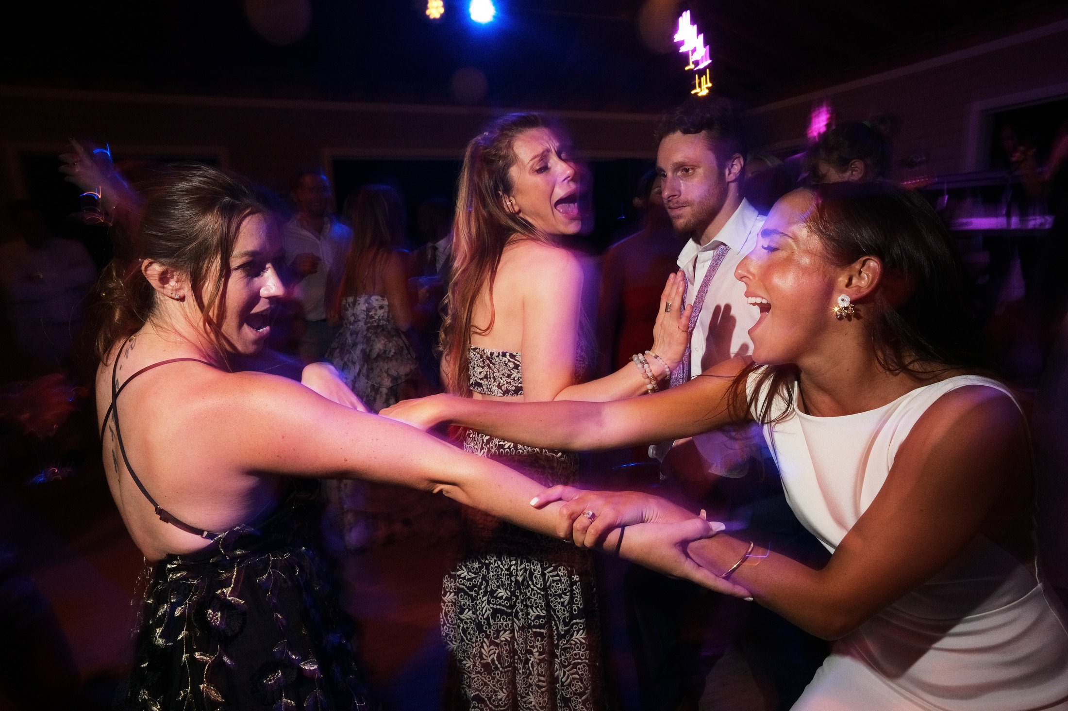 People dancing and having fun at a party or celebration, with colorful lighting.