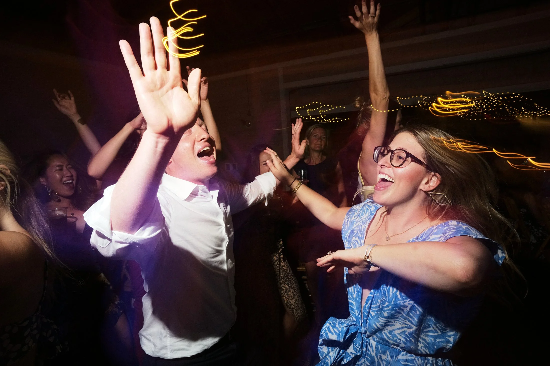 People dancing and having fun at a party, with lights and motion blur.