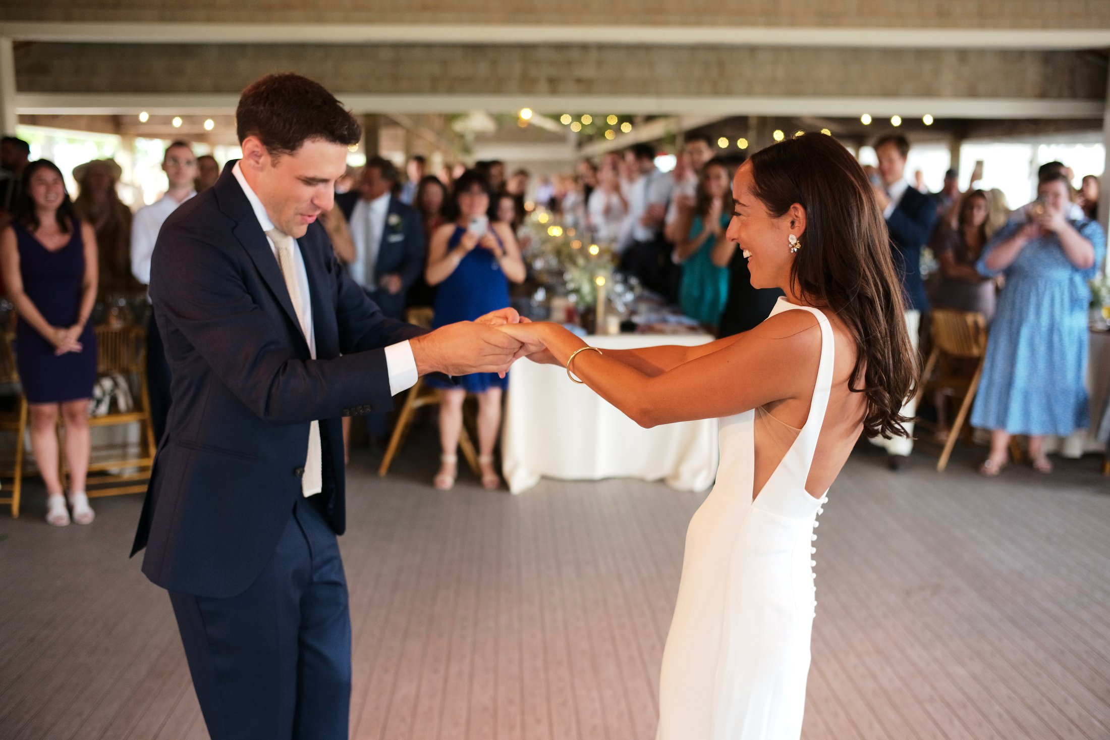 A bride and groom dance during their wedding reception, with guests watching in the background.