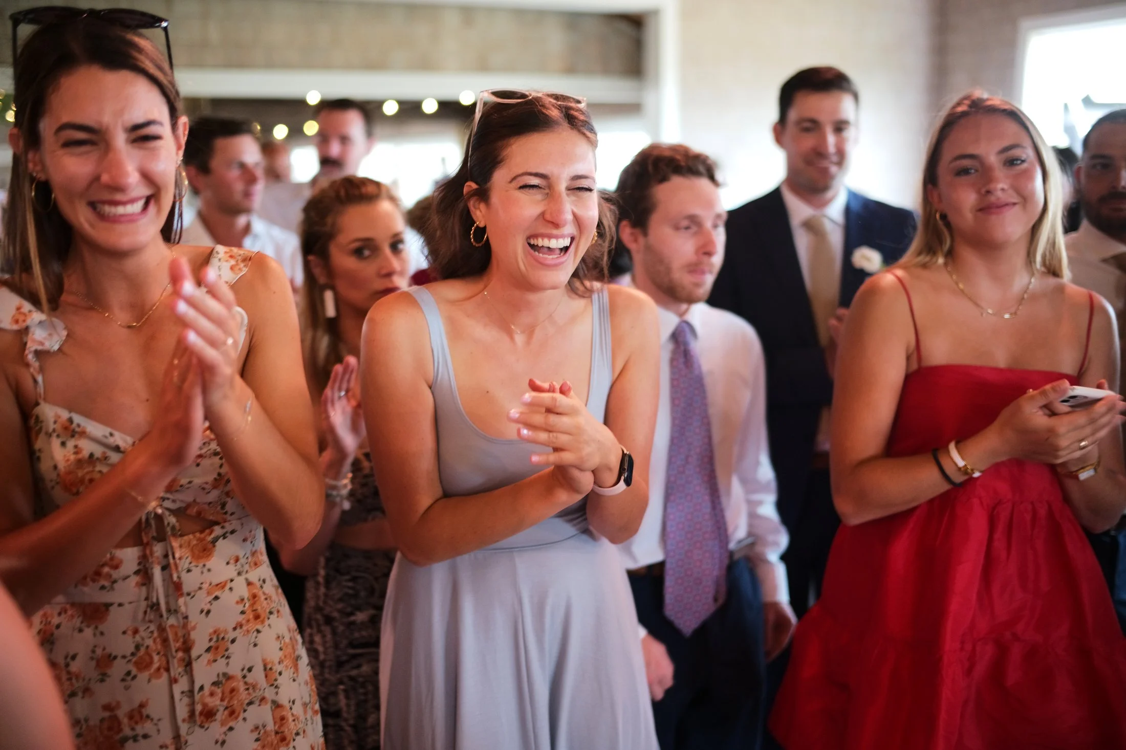 Group of people at a celebration, having fun and smiling, indoors with warm lighting.