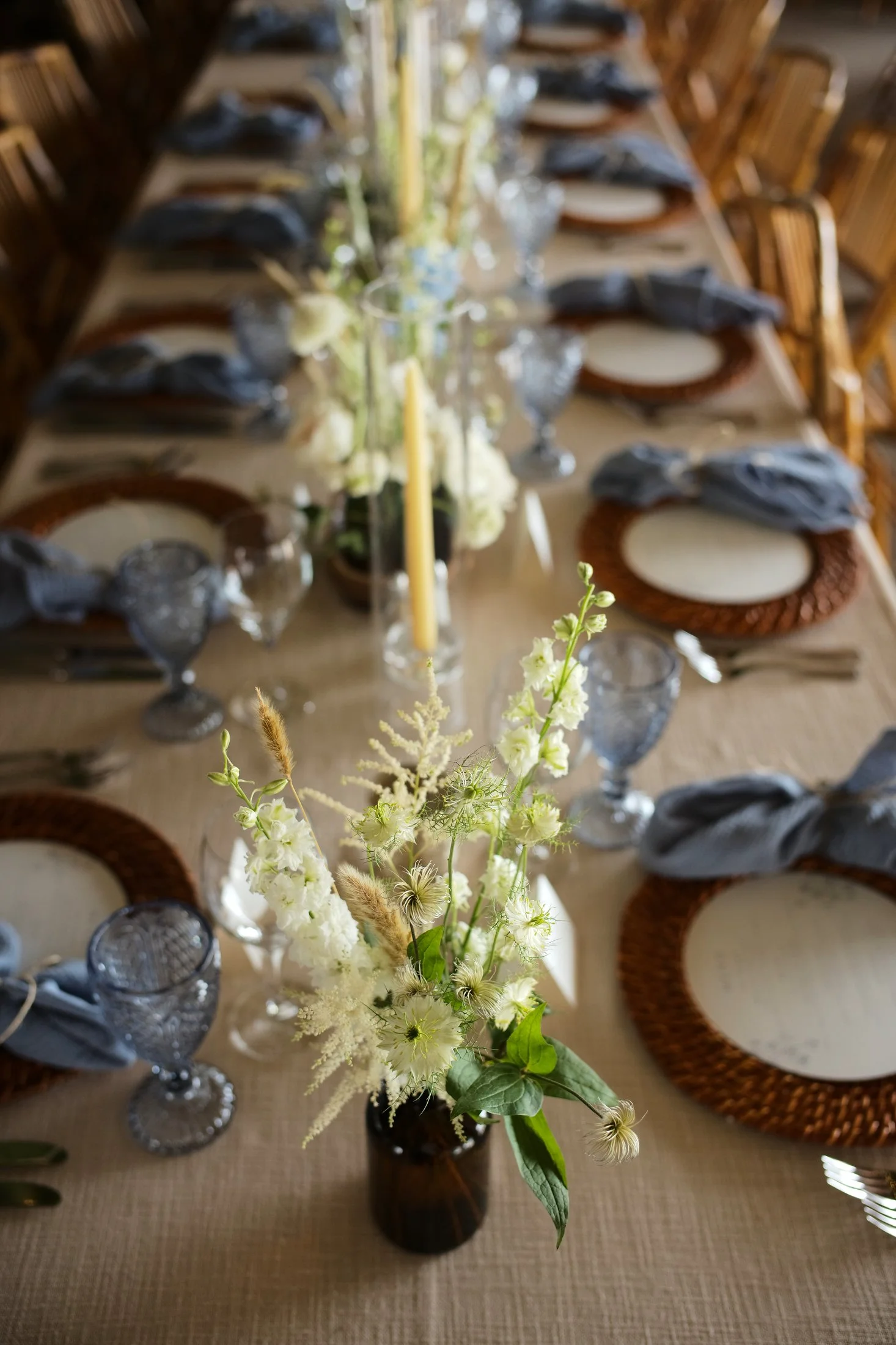 Close-up of a floral centerpiece on a dining table with table settings, glassware, and napkins.