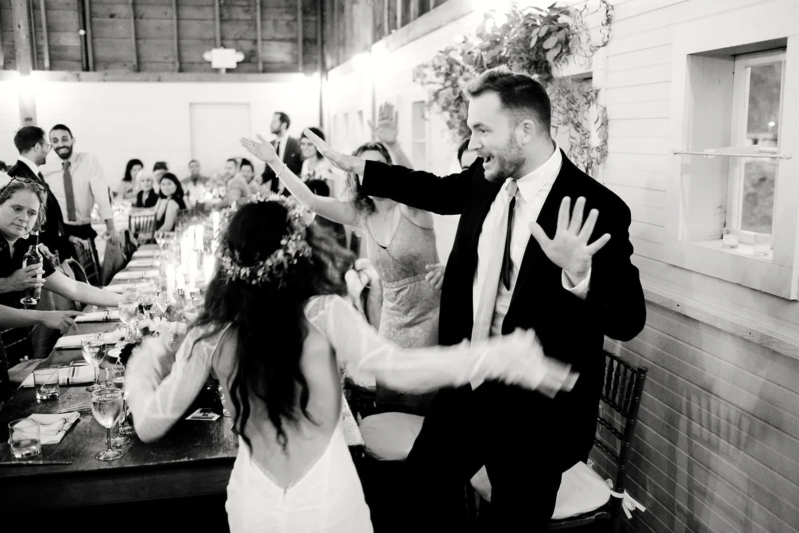 People celebrating at a wedding reception, dancing and enjoying themselves in a rustic decorated venue.