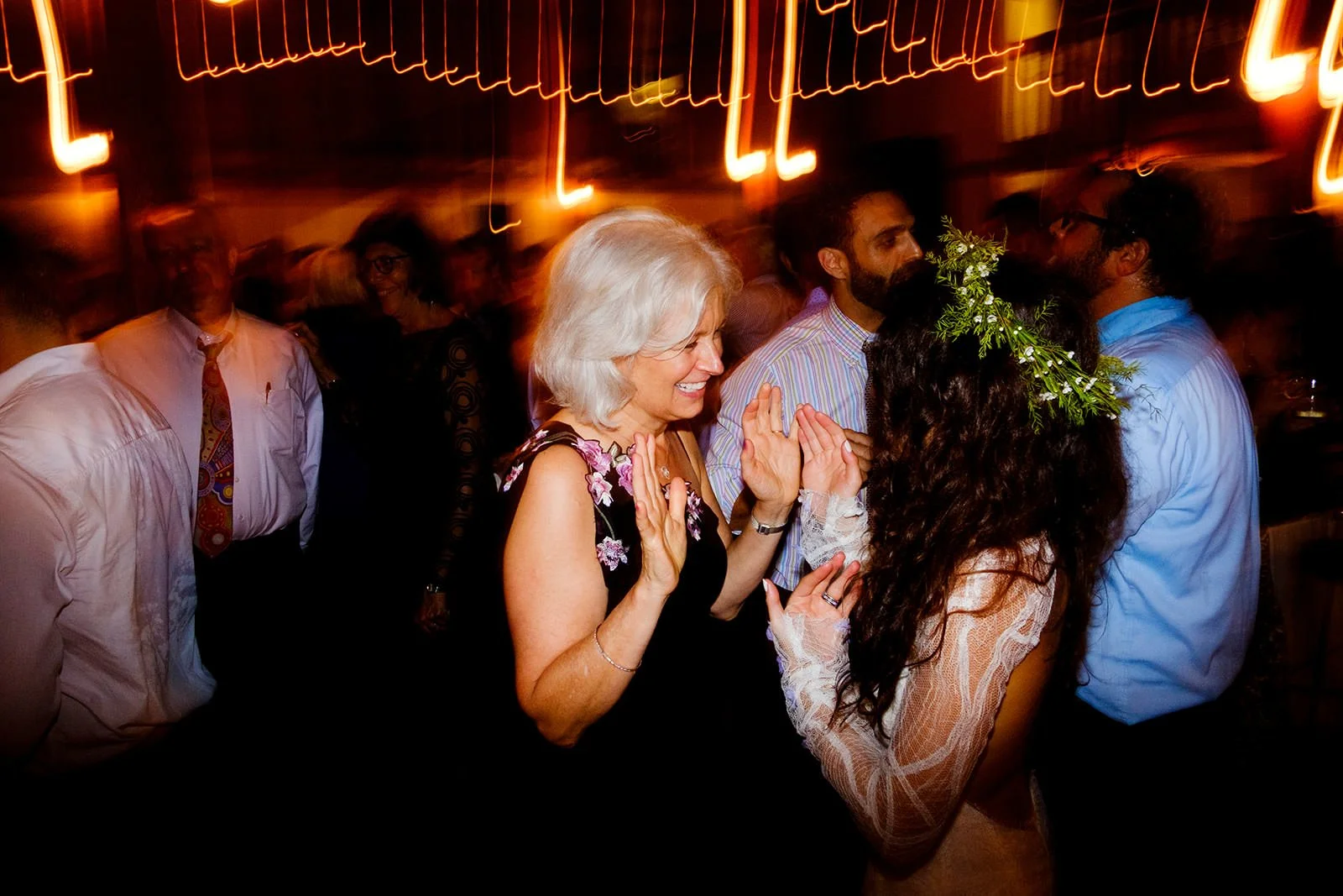 People dancing and celebrating at a party with blurred, colorful lights in the background.