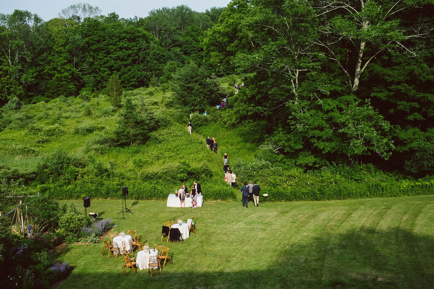 Candid wedding photographer boston captures guests walking up the hill to the wedding ceremony site.