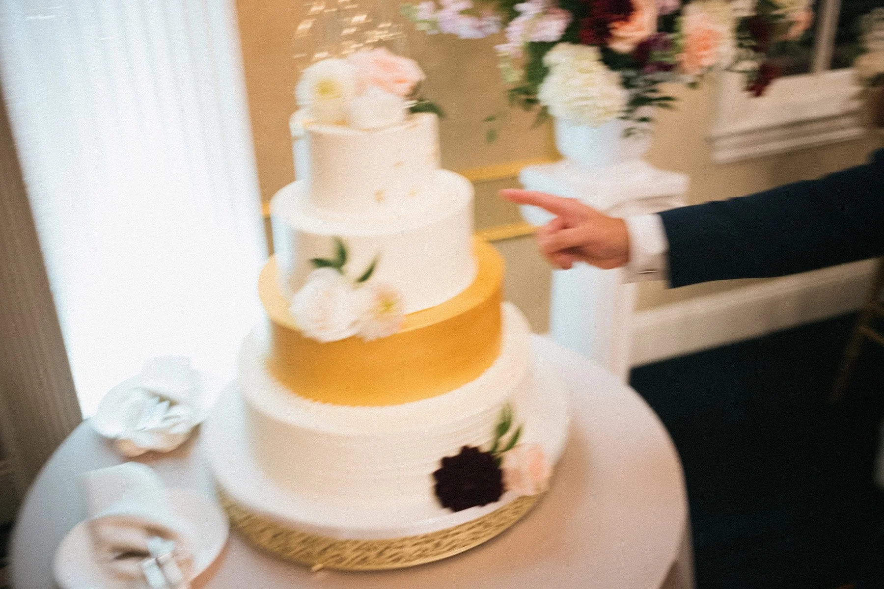 Candid wedding photographer makes images like this photo of a finger snitching wedding cake
