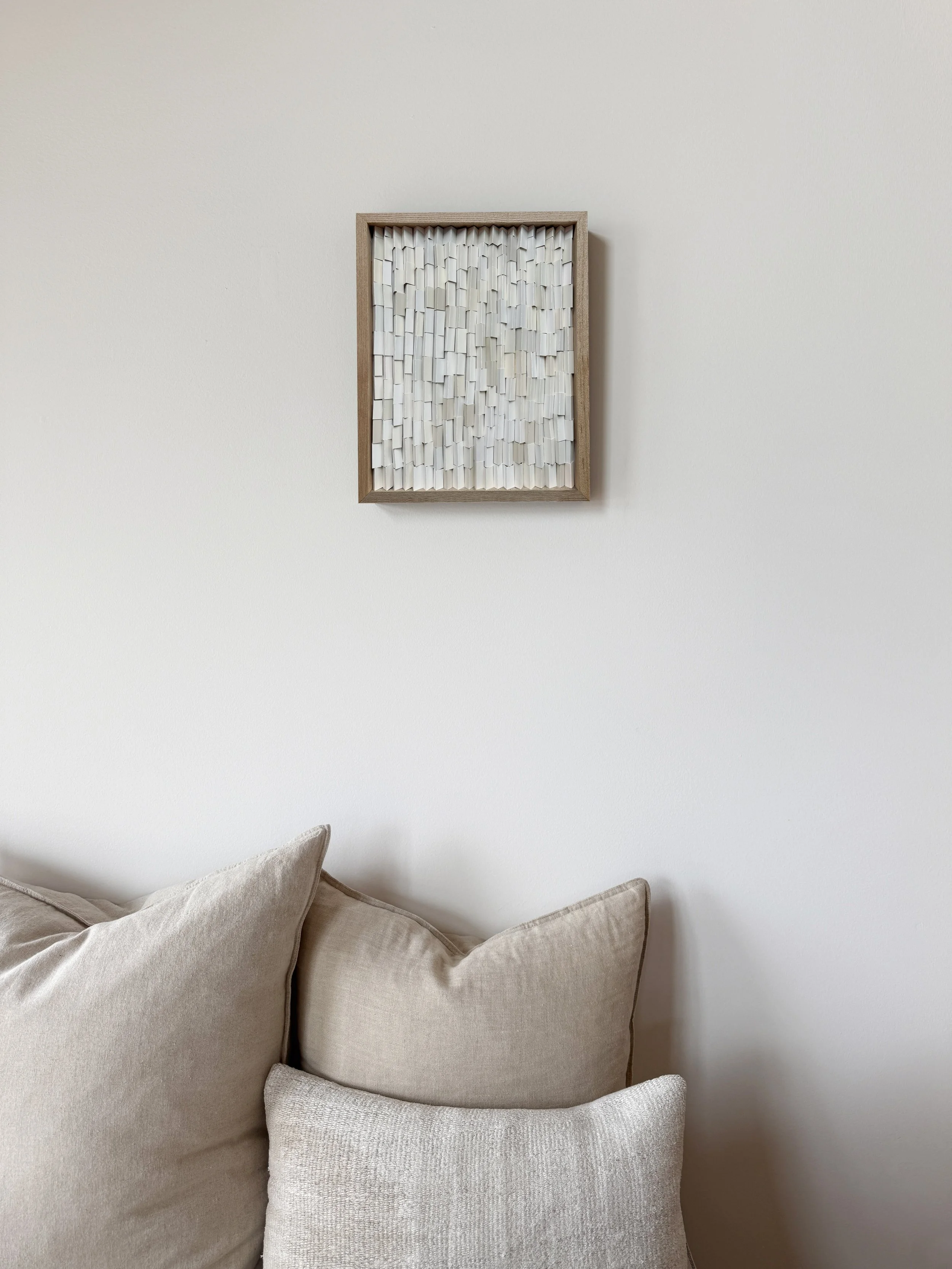 Minimalist home decor with neutral art, a beige sofa and pillows.  White and beige abstract textured wall art, made of reclaimed paint swatches. Arist based in Vernon, BC, Canada.