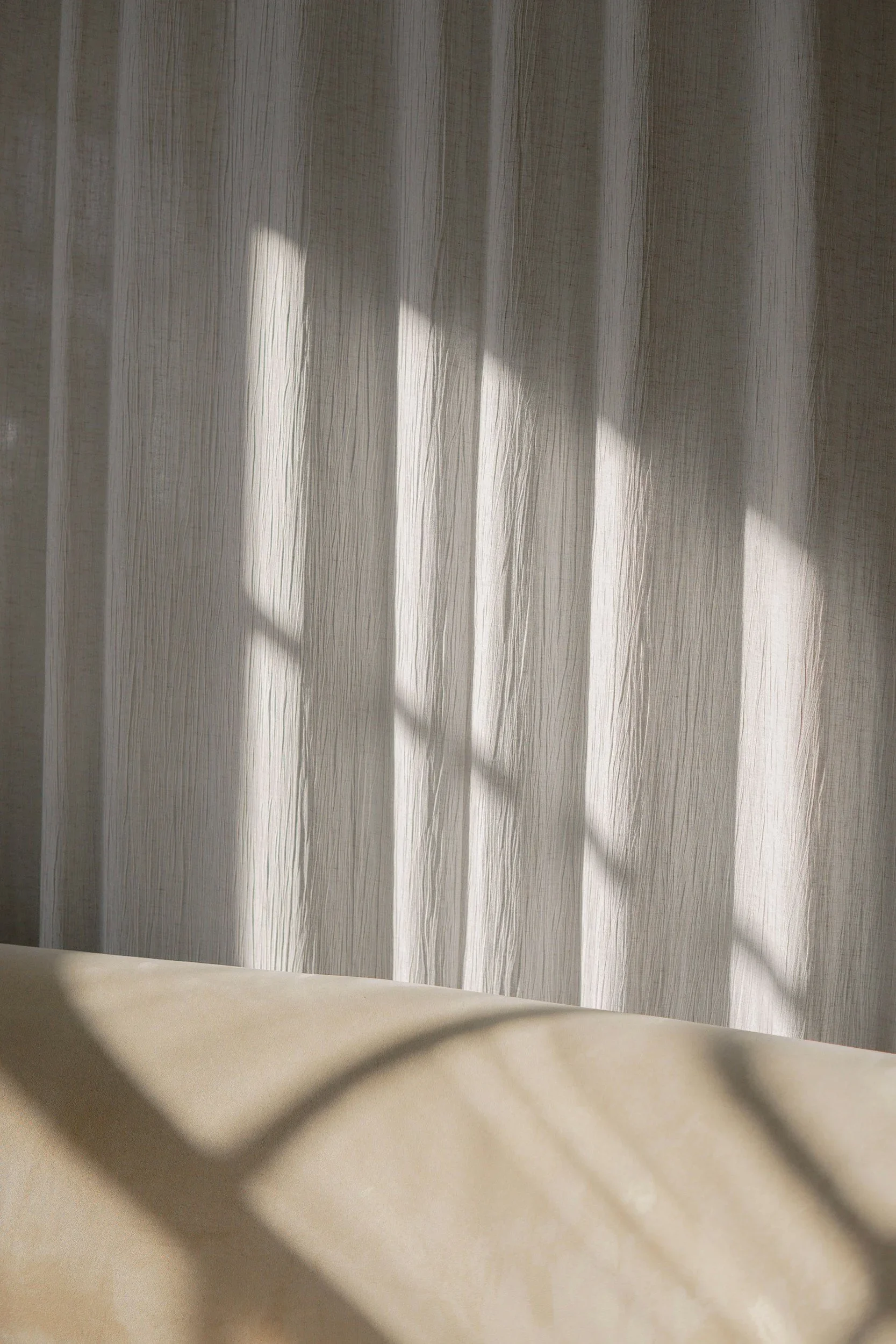 Sunlight streaming through sheer curtains onto a neutral interior.