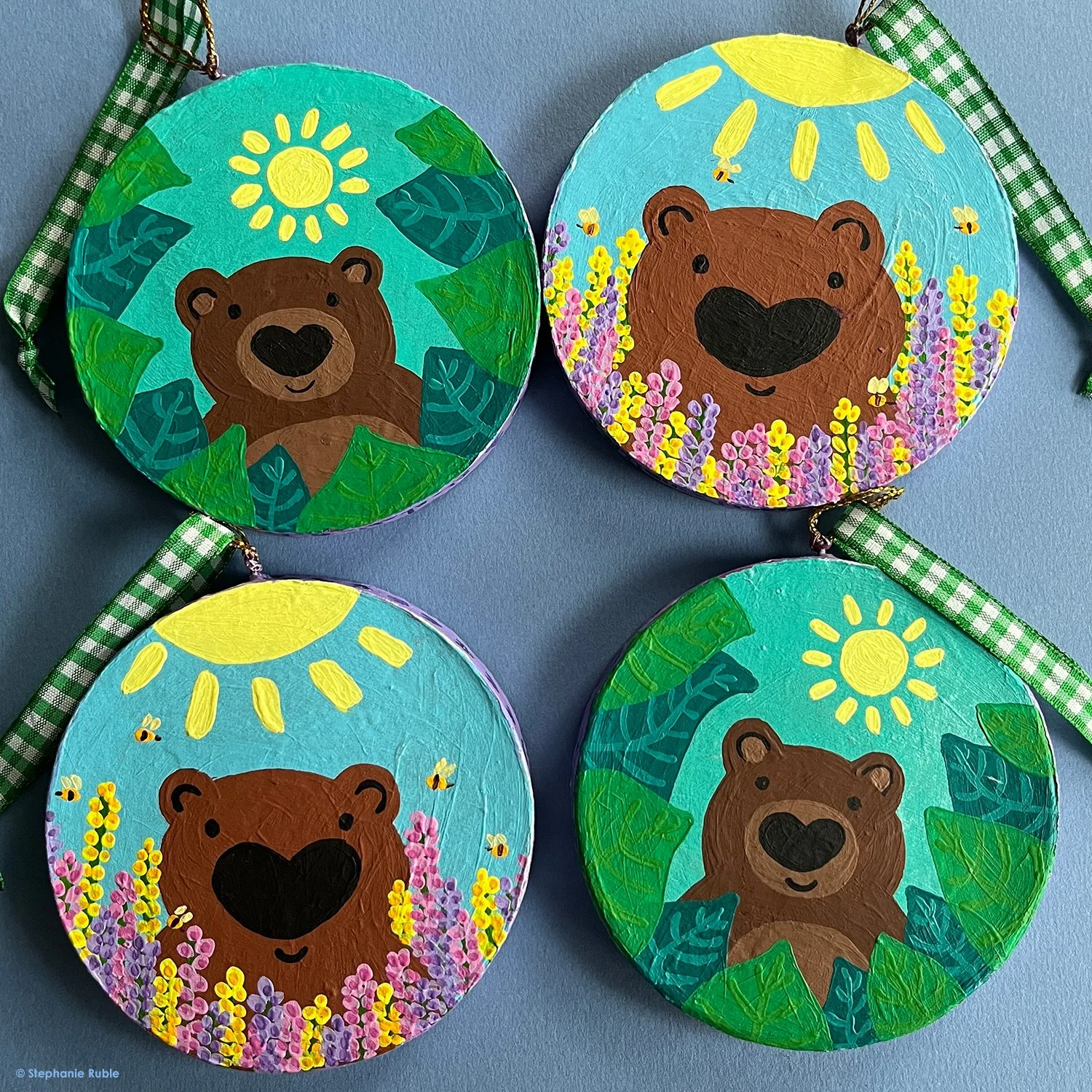4 bear ornaments, with 2 scenes: 1. (top right/bottom left) bear in field of flowers 2. (top left/bottom right) bear peeking out from leaves