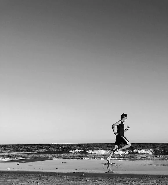 Fotografia a preto e branco de uma pessoa a correr junto ao mar, Evocando a passagem do tempo e as memórias da infância.