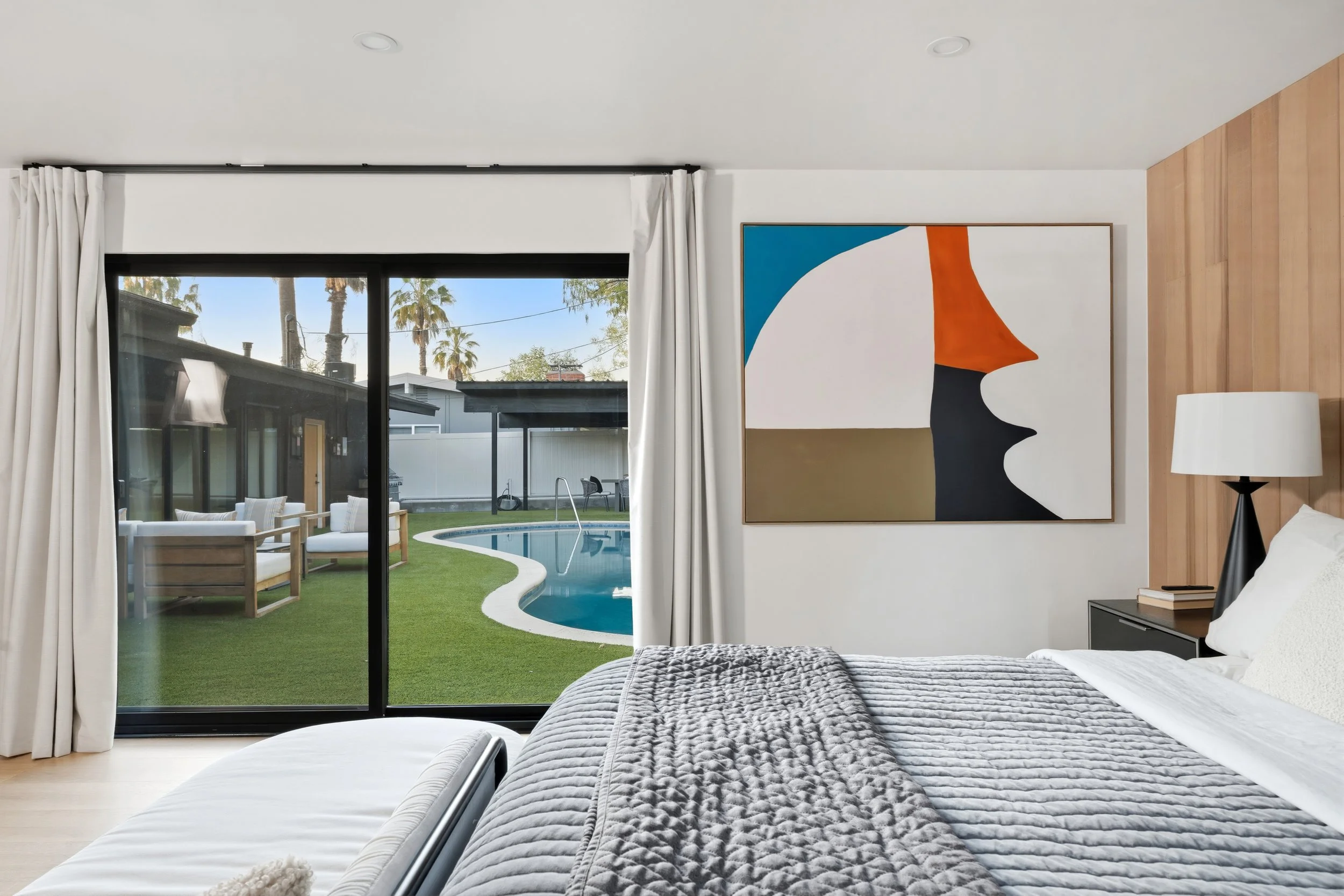 Bedroom with large sliding glass door view of backyard with pool and outdoor seating.