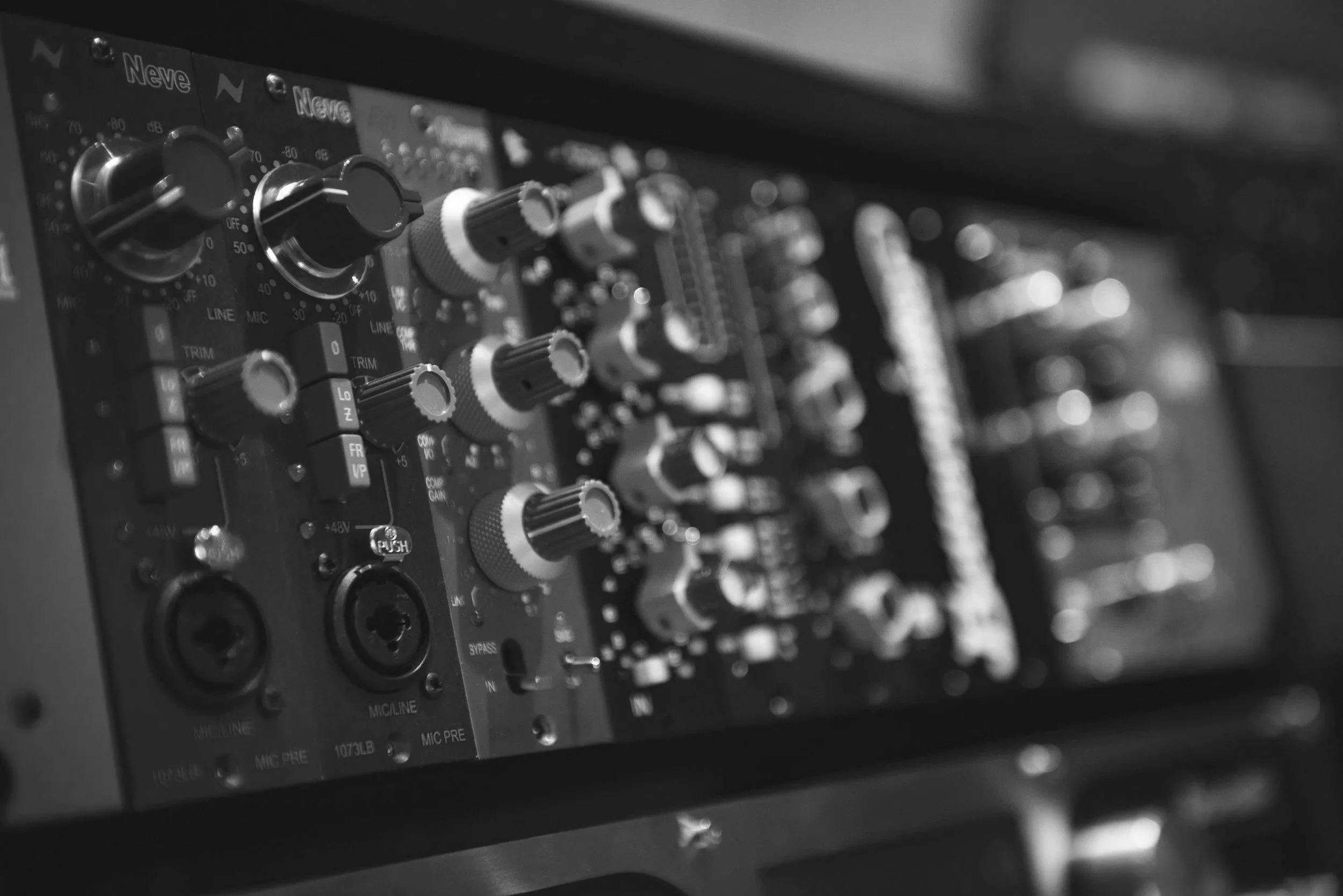 Close-up of a professional audio mixing console or soundboard with various knobs and controls.