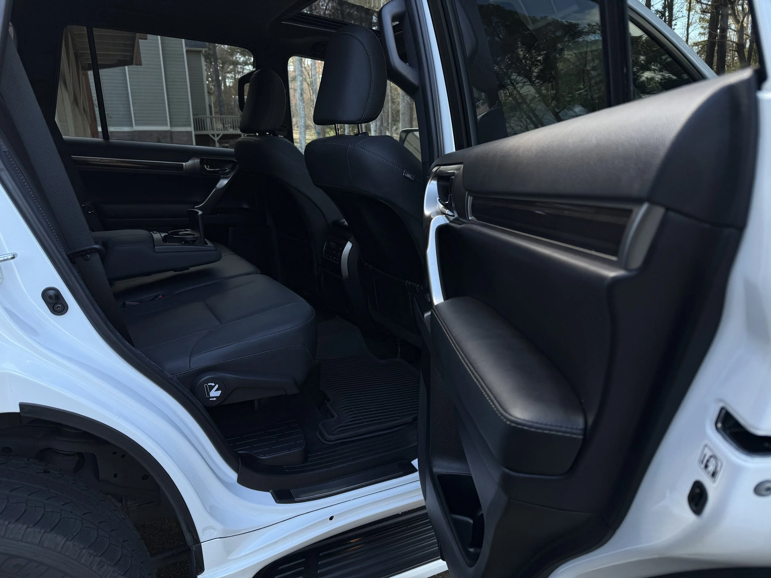Interior of a white vehicle showing black leather back seats, with the rear door open.
