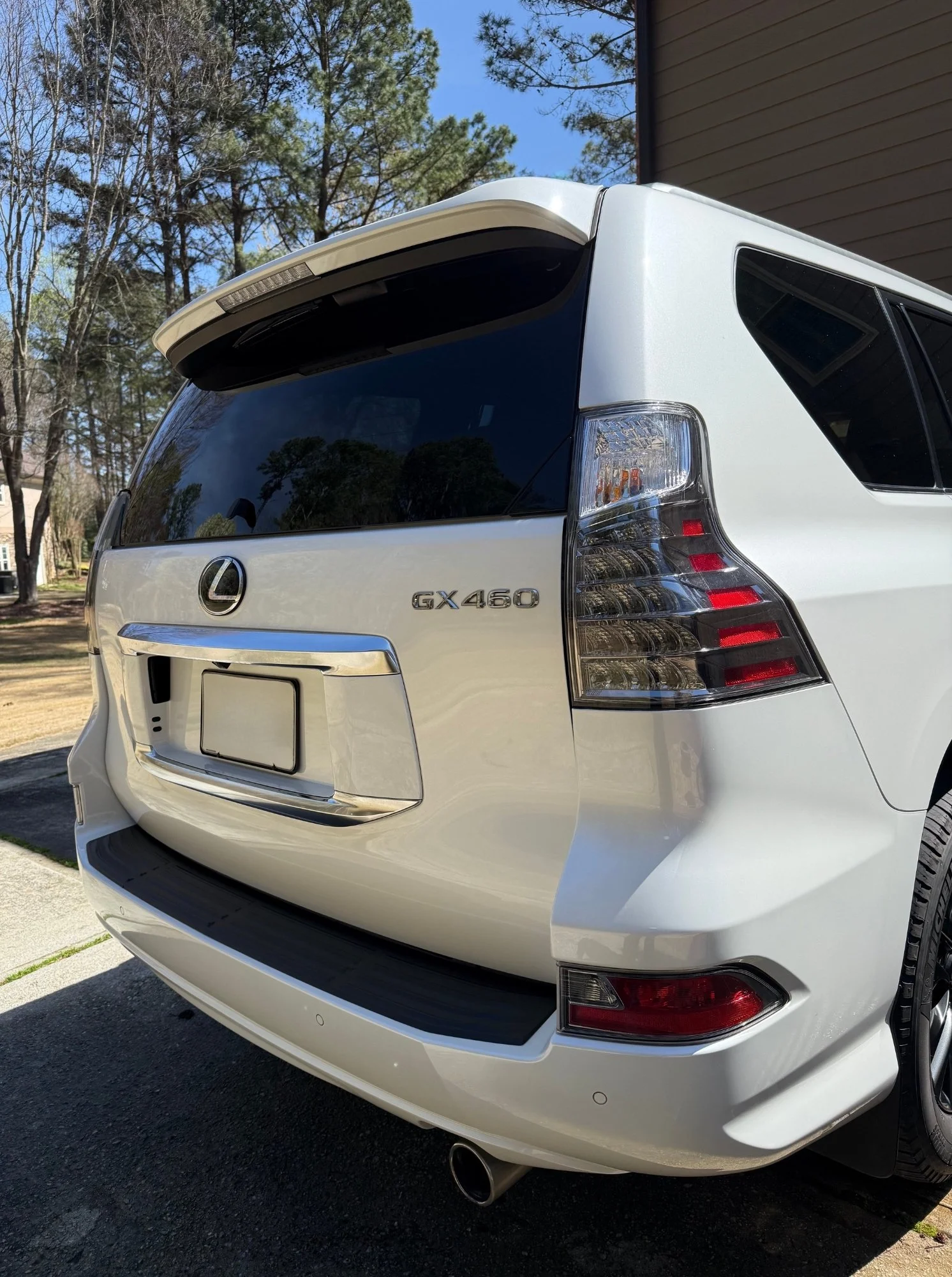 Rear view of a white Lexus GX 460 SUV parked outside, showing the tail lights, rear window, and license plate area.