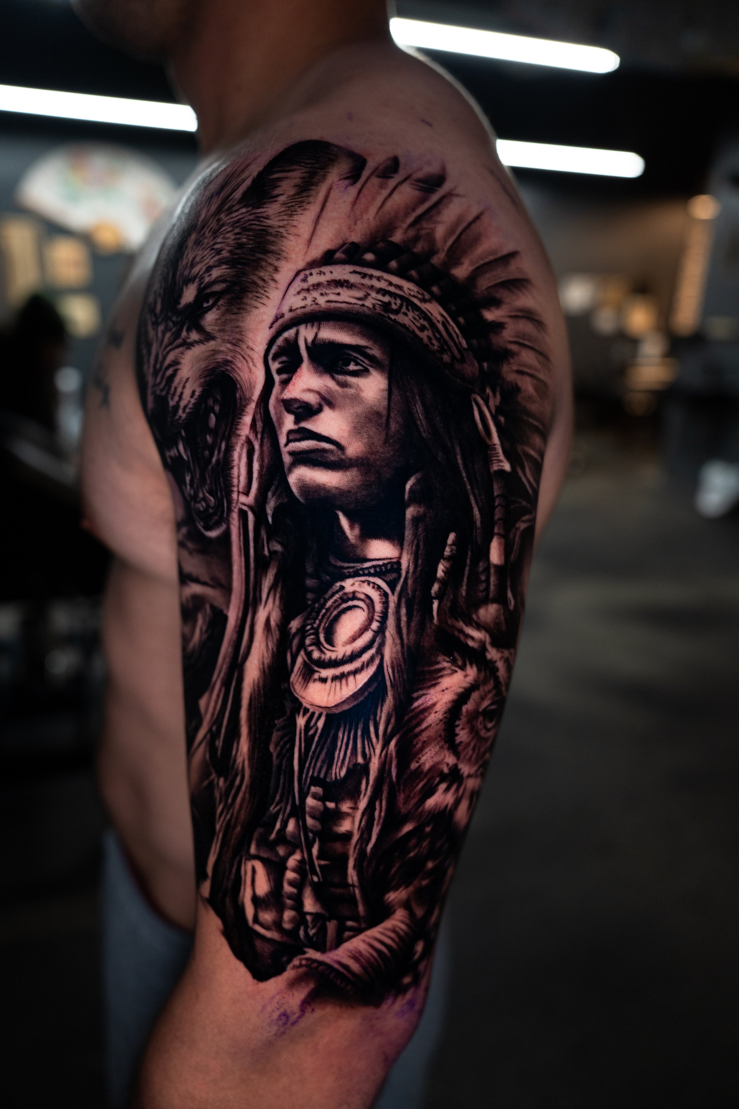 Tattoo of a Native American chief wearing a feathered headdress on upper arm