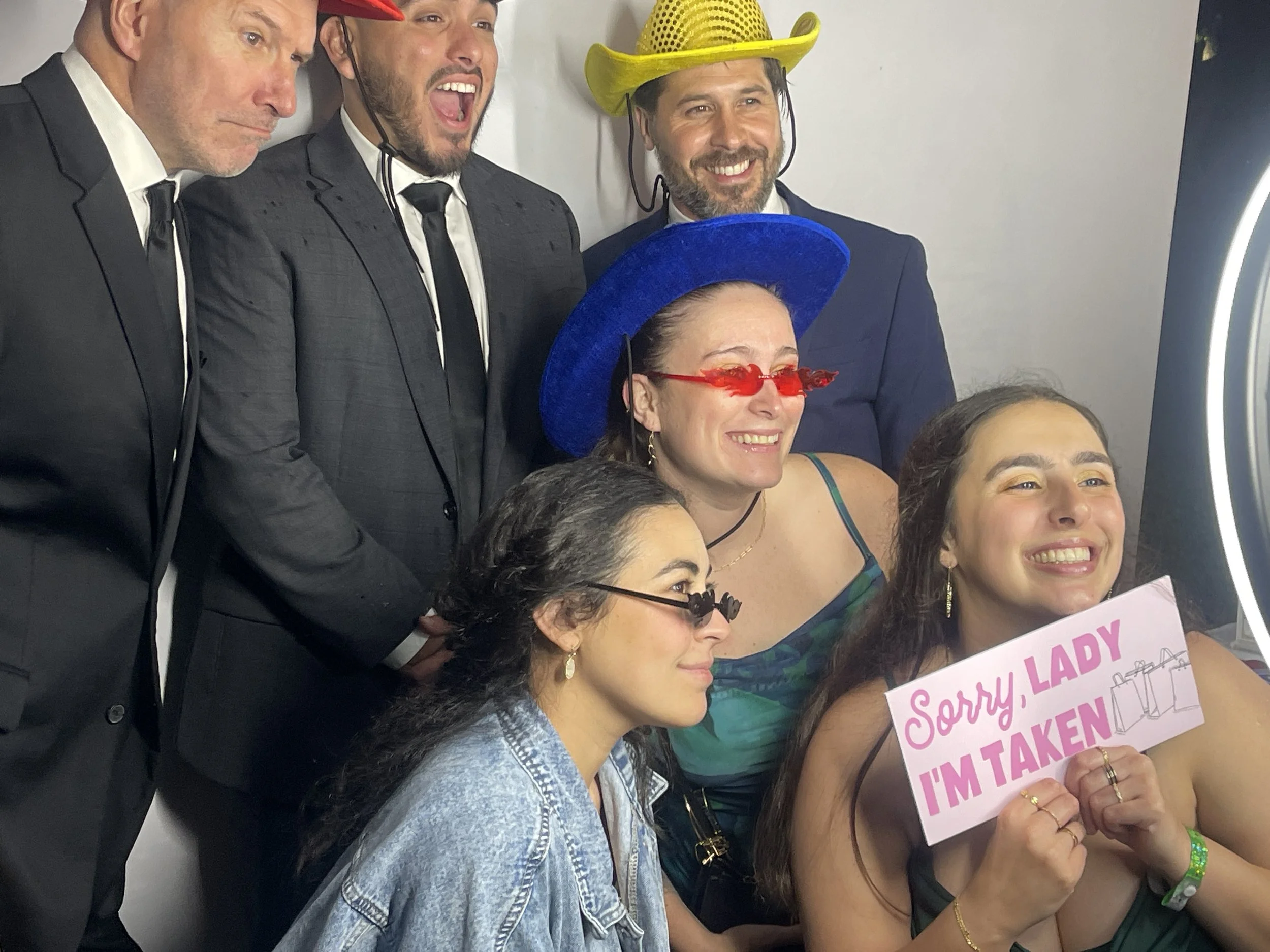 Guests in formal attire posing with fun props at a luxury digital photo booth rental for a celebration in New Orleans
