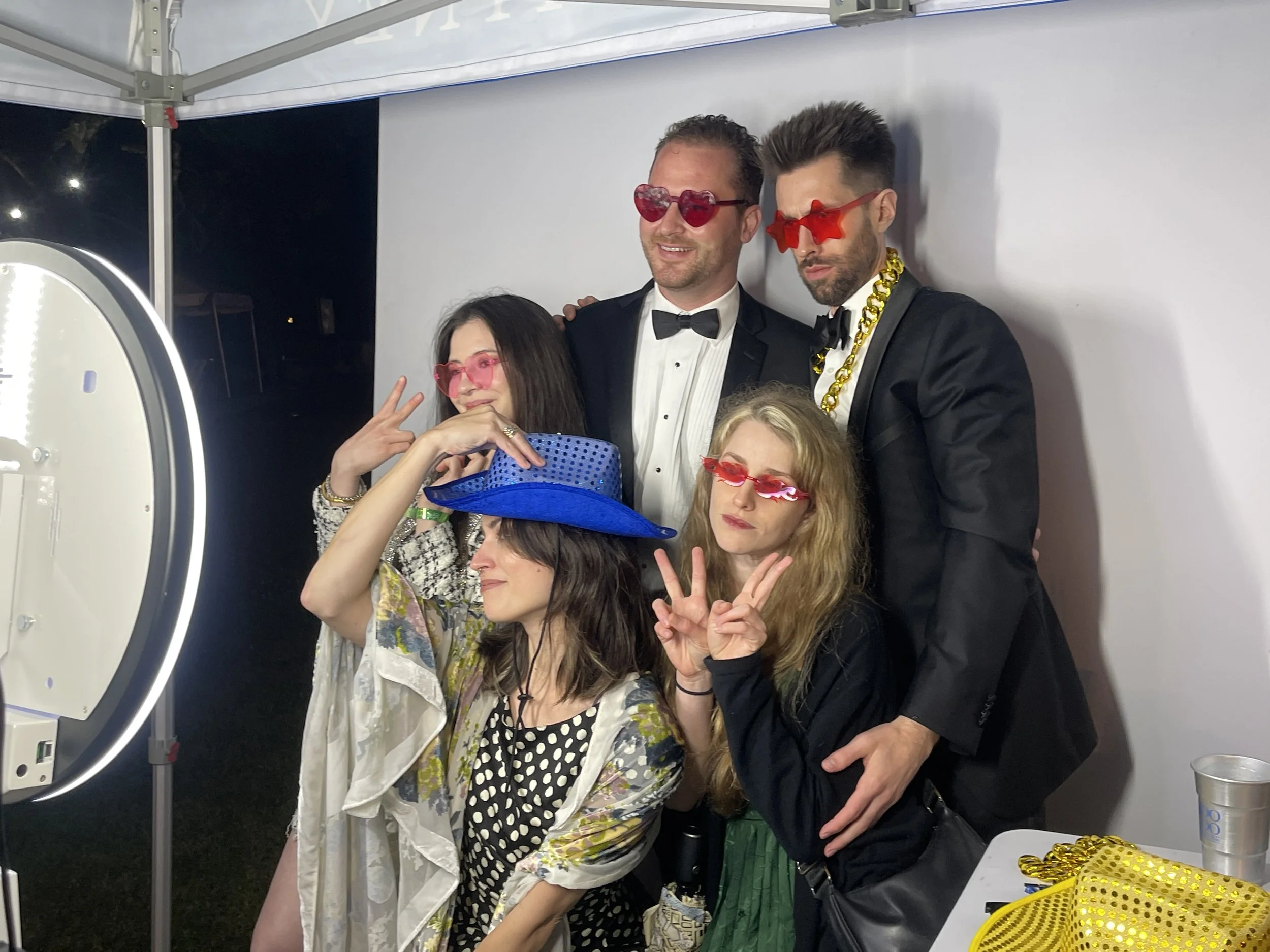 Guests in formal attire posing with fun props at a luxury digital photo booth rental in New Orleans