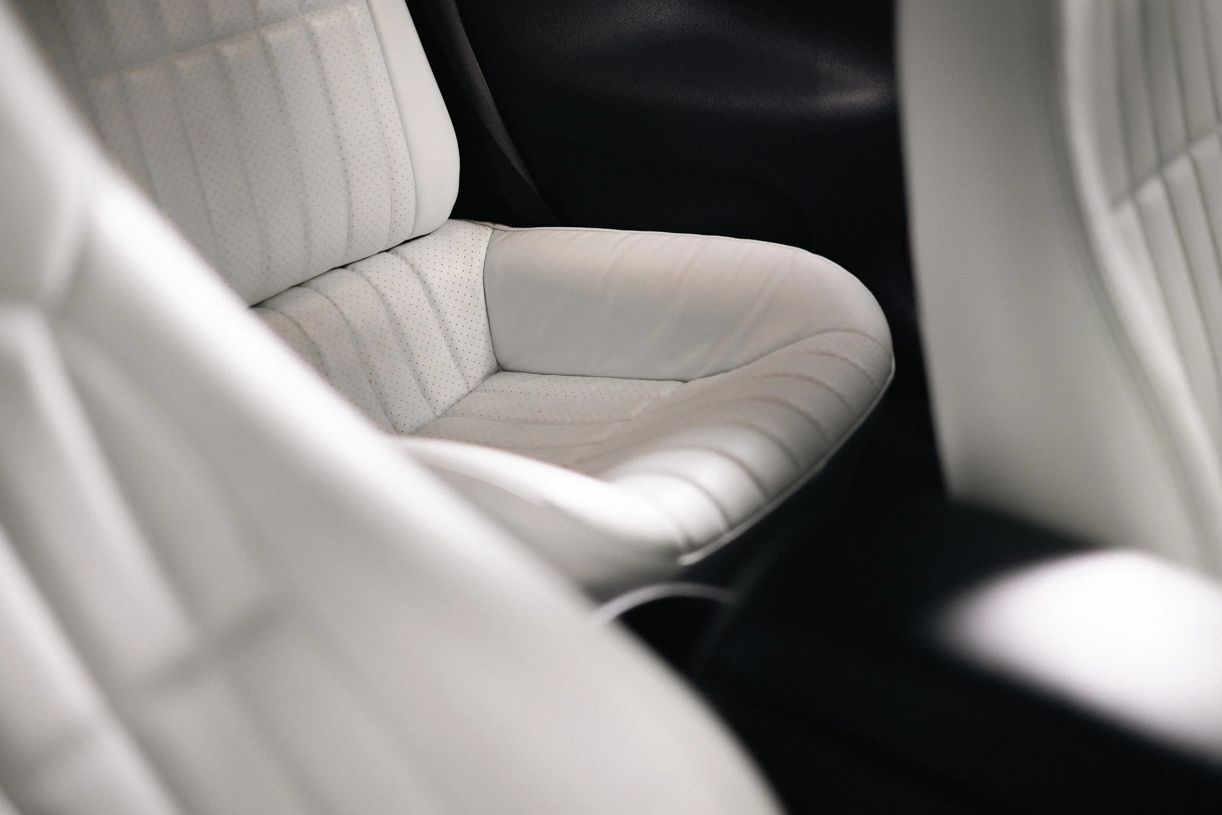Close-up of a cream-colored leather car seat with perforated detailing, partially visible in the image.