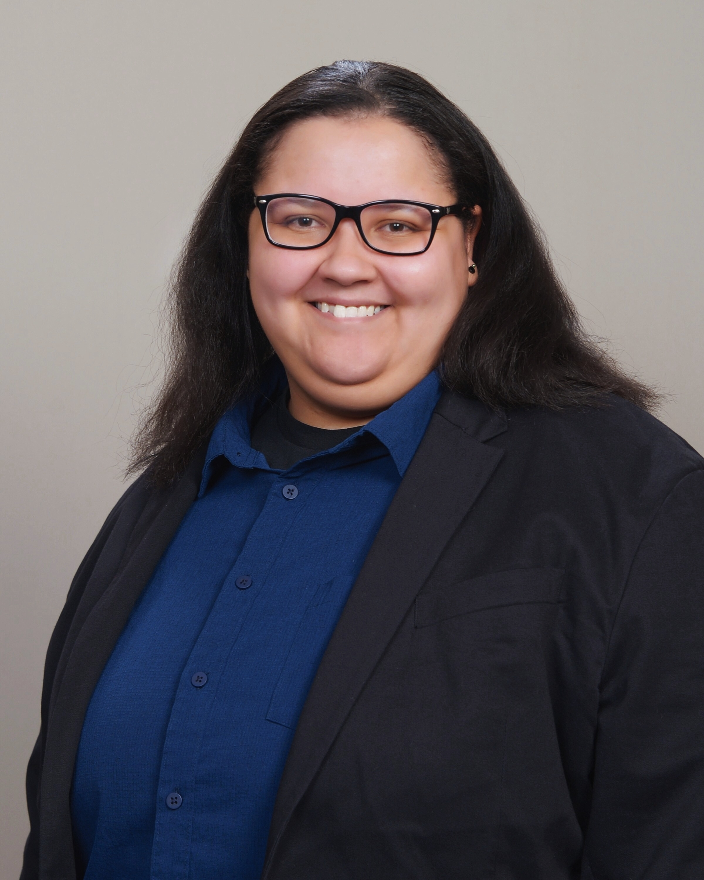 Professional headshot of Holly E. Burgess, PhD Candidate, smiling in a black blazer and blue button-down shirt
