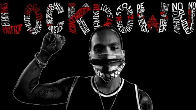 Black and white photo of Anderson .Paak with his fist raised in a Black Power stance with "lockdown "typography. A still from his music video, "Lockdown"