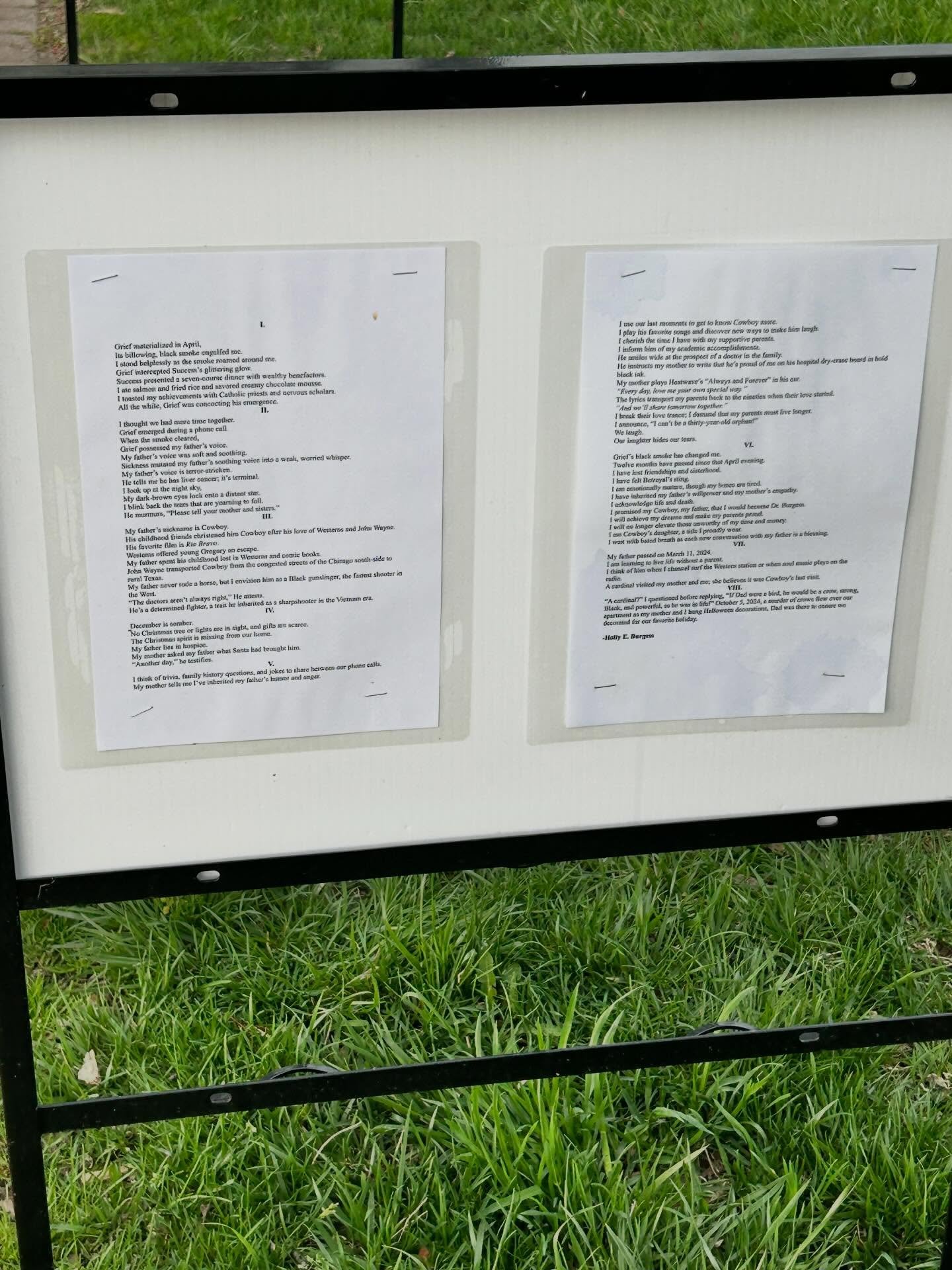 "With Bated Breath (In Memory of Greg)" poem by Holly E. Burgess on display outside of Lake Geneva Public Library by a white posterboard attached to a black metal frame.