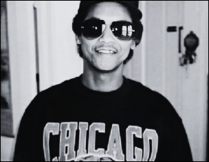 A black-and-white portrait of the author's father, Greg Burgess, smiling, wearing a Chicago Bears t-shirt, a baseball cap, and sunglasses.