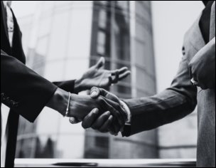 A firm handshake between two Black professionals symbolizes collaboration, service, and community partnership.