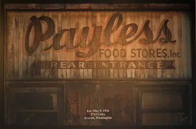 Wooden sign for Payless Food Stores Inc. with additional text for rear entrance and address in Everett, Washington.