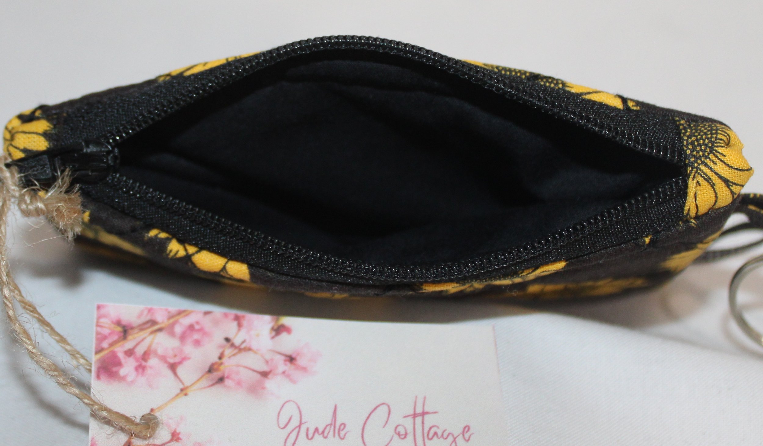 Top view of dark quilted keychain wallet with bright sunflower pattern, zipper closure, and metal key ring.