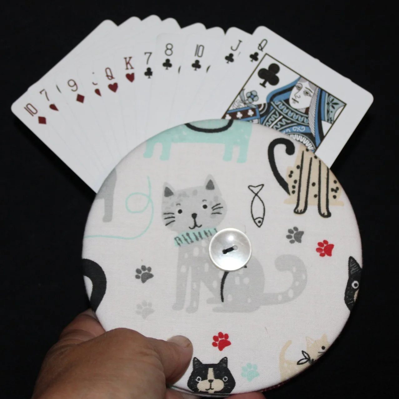 Front view of the Kitty Days Card Holder featuring an assortment of cats and floral accents shown being held in use with an assortment of playing cards.