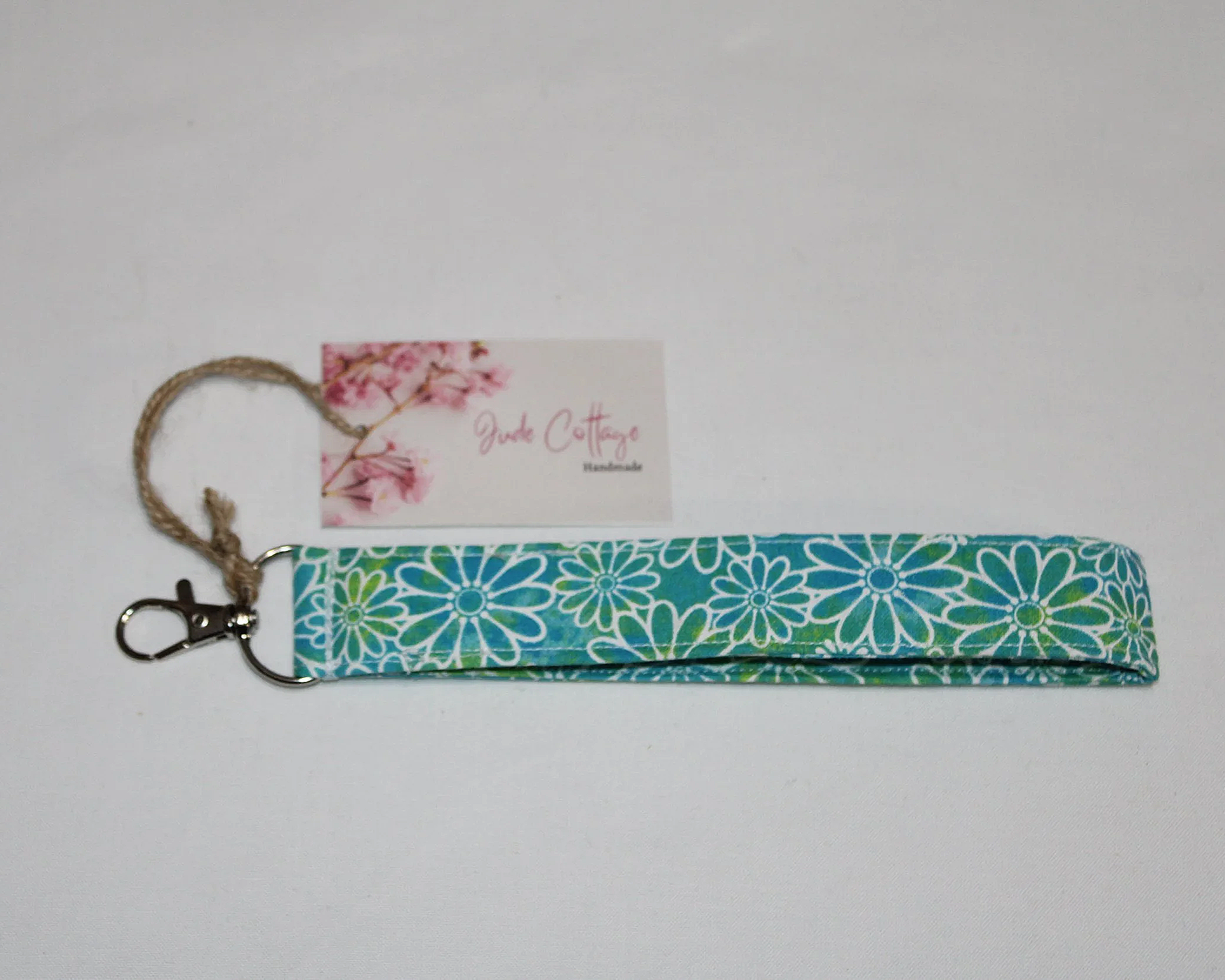 Neon Daisy Wristlet made from bright multicolor daisy‑print fabric with an approximately 7.5‑inch strap, metal clasp, and branded tag, displayed on a neutral background.