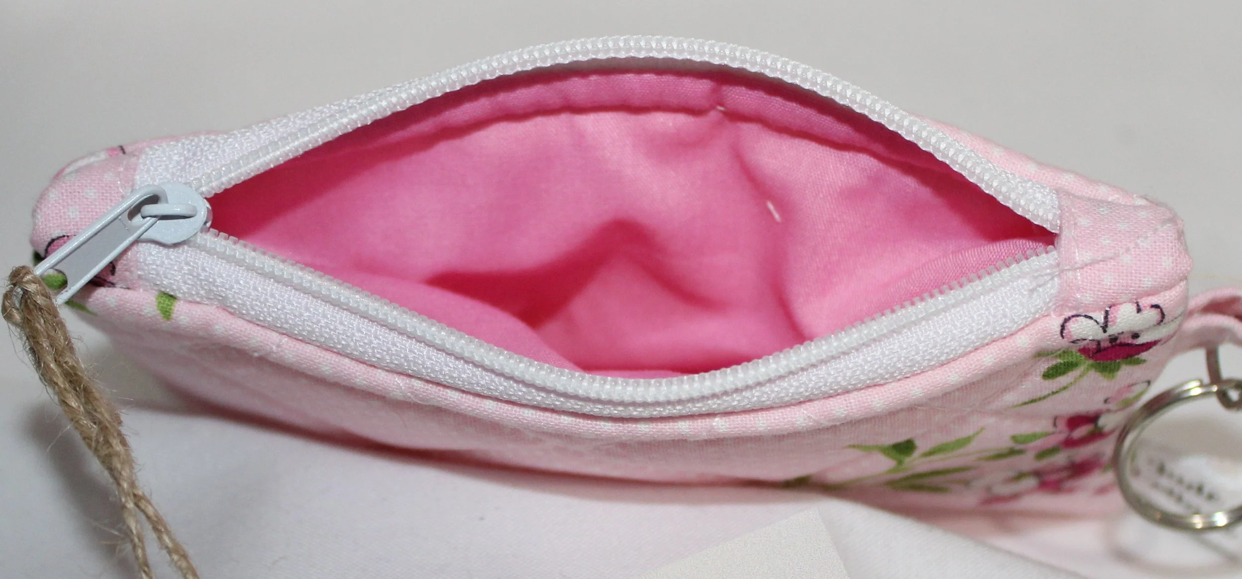 Top view pink quilted keychain wallet with cherry blossom floral pattern, zipper closure, and metal key ring.