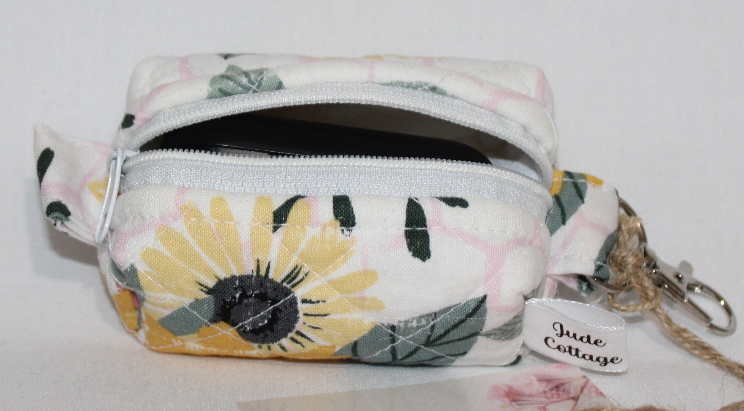 Open top view of the Honeycomb Sunflower Bag Charm featuring a white fabric with pink honeycombs and yellow sunflower print, shown with a J Lab earbud case inserted for sizing reference.