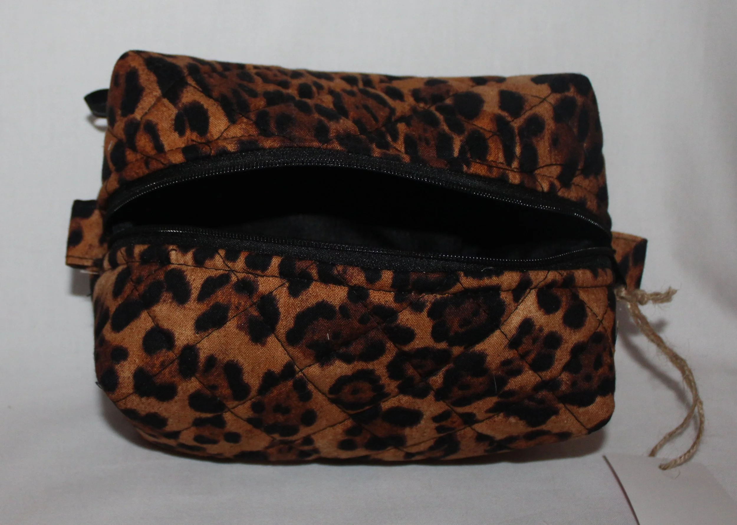 Open‑top view of the Lyra quilted travel pouch in brown and black leopard fabric with the empty interior visible.