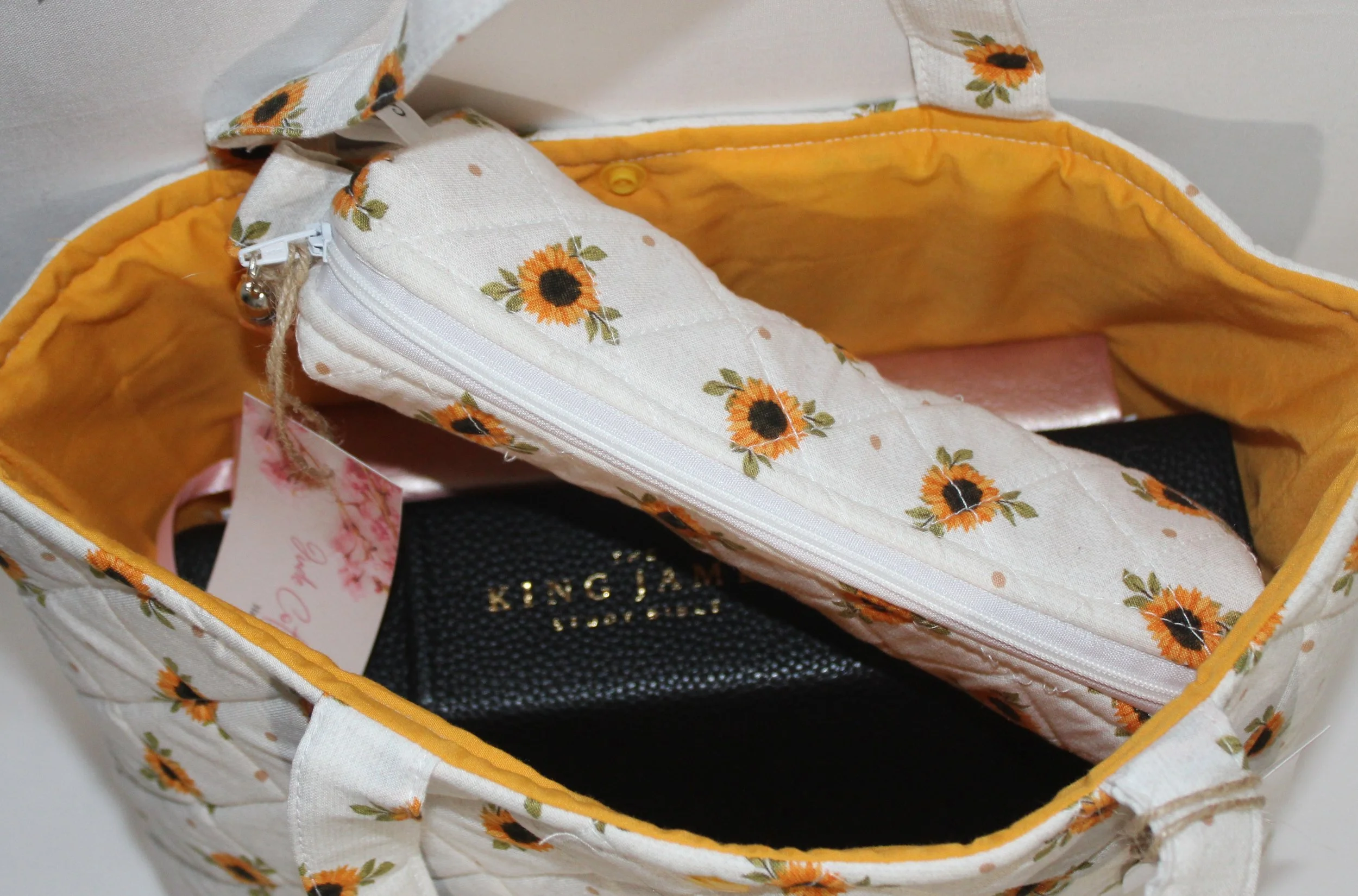 Top view of the Sunflower Medley quilted Bible sleeve, with a study Bible, notebook, and pencil pouch inserted to show sizing.