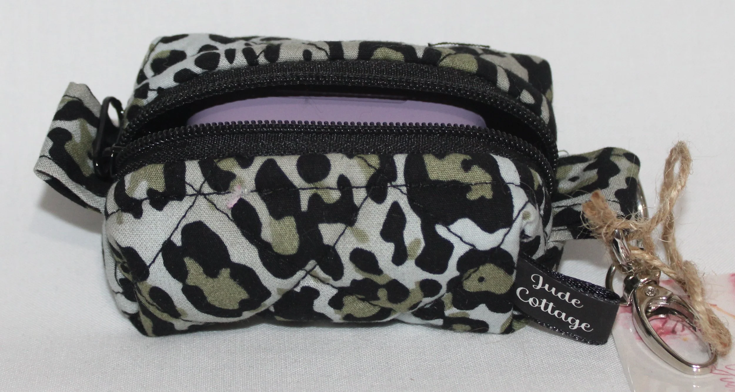 Open top view of the Diana Bag Charm featuring snow leopard print showing a set of J Lab earbuds inserted for sizing.